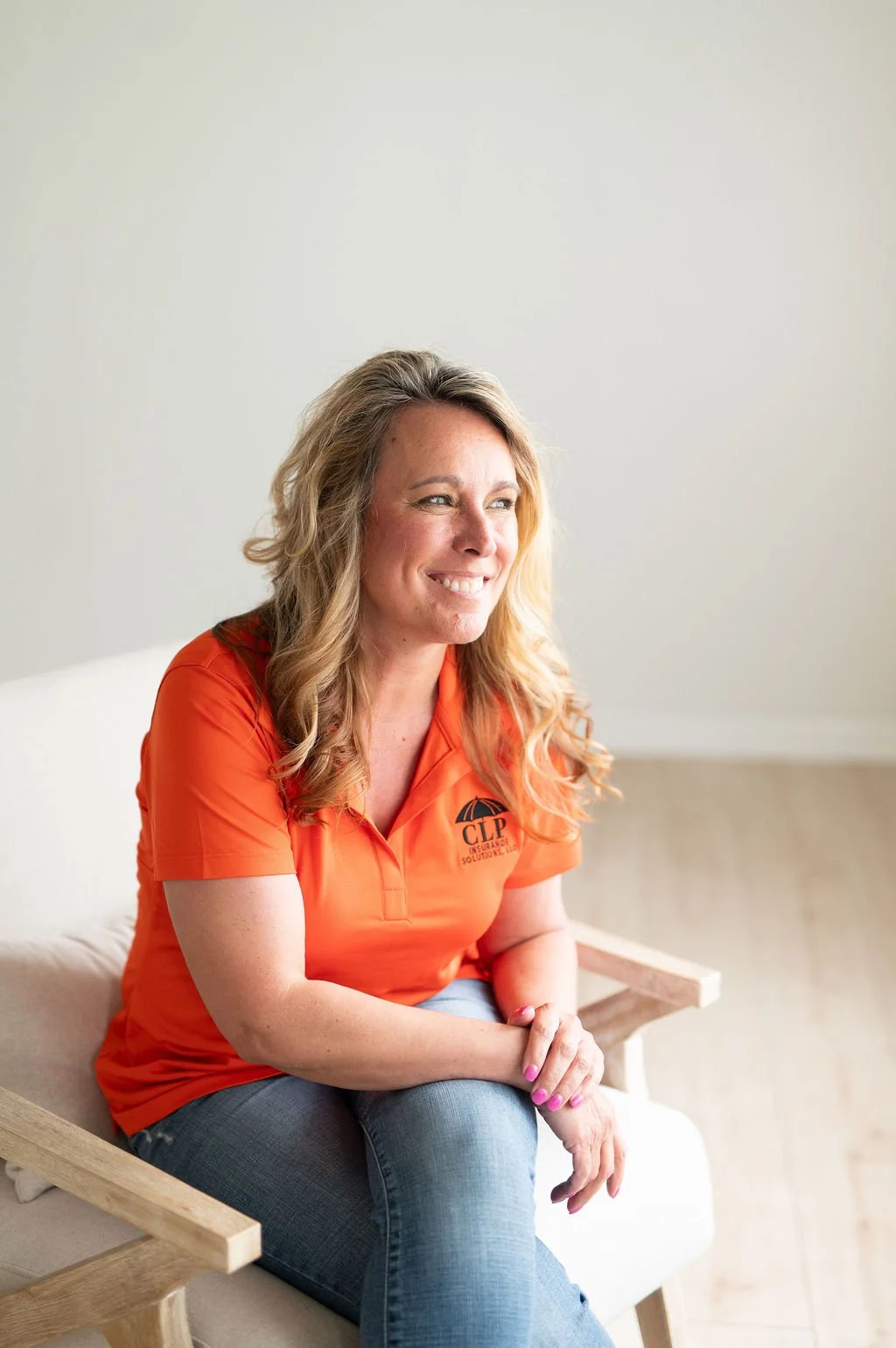Smiling owner of CLP Insurance Solutions, an Illinois Local member business, wearing an orange company polo