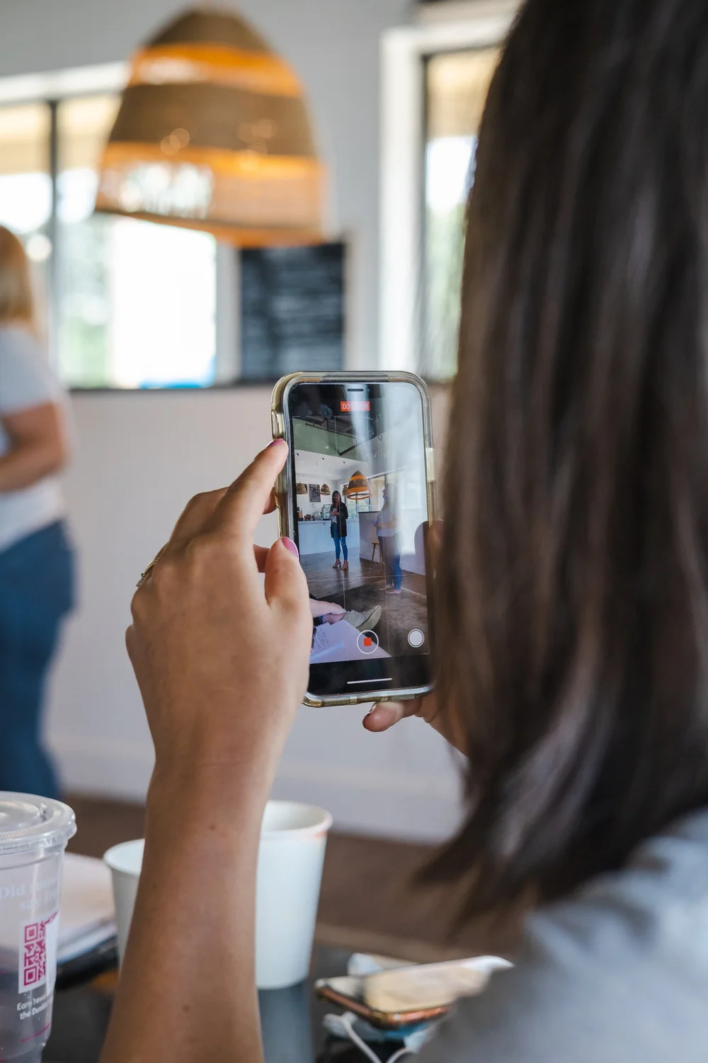 Person photographing a dish with a smartphone inside a local cafe