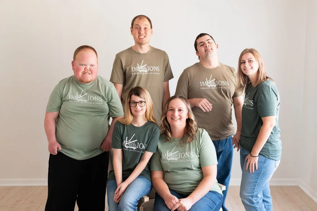 The Impressions team, an Illinois Local member business, smiling together in matching green Impressions t-shirts