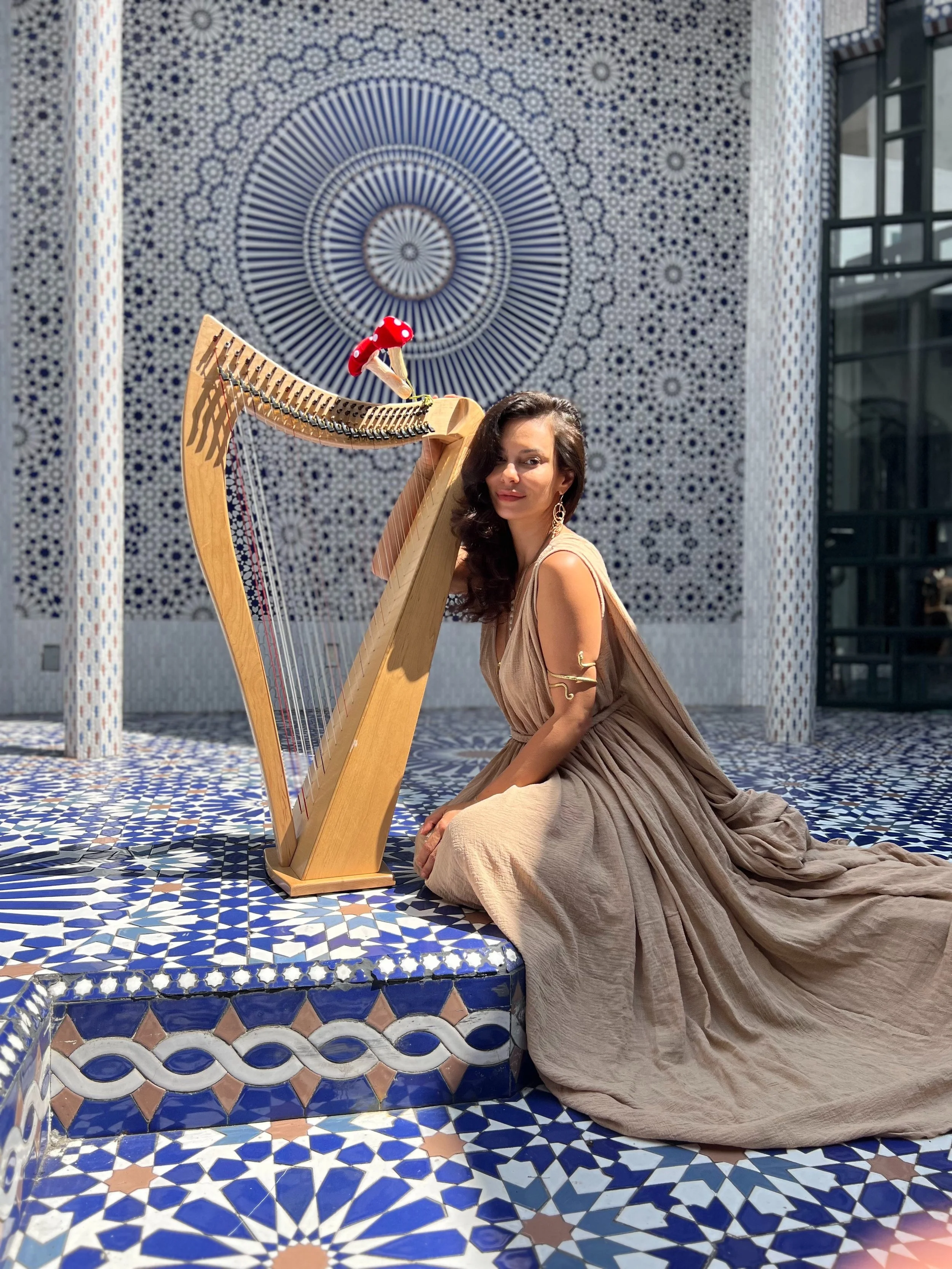 Scarlett playing harp in a tiled Moroccan courtyard