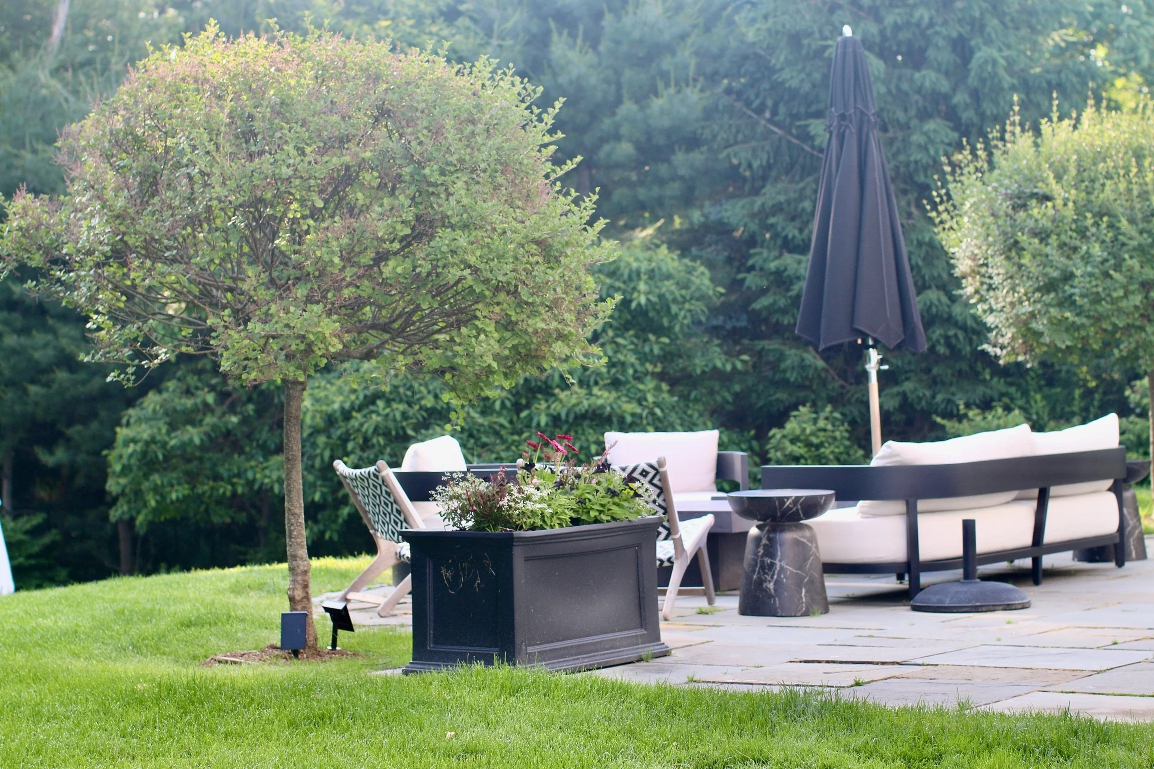 Stone patio with a planter of flowers and outdoor seating
