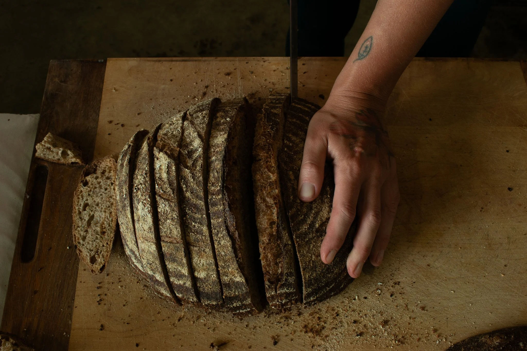 Lydia slices beautiful sourdough bread, made with Meadowlark flours