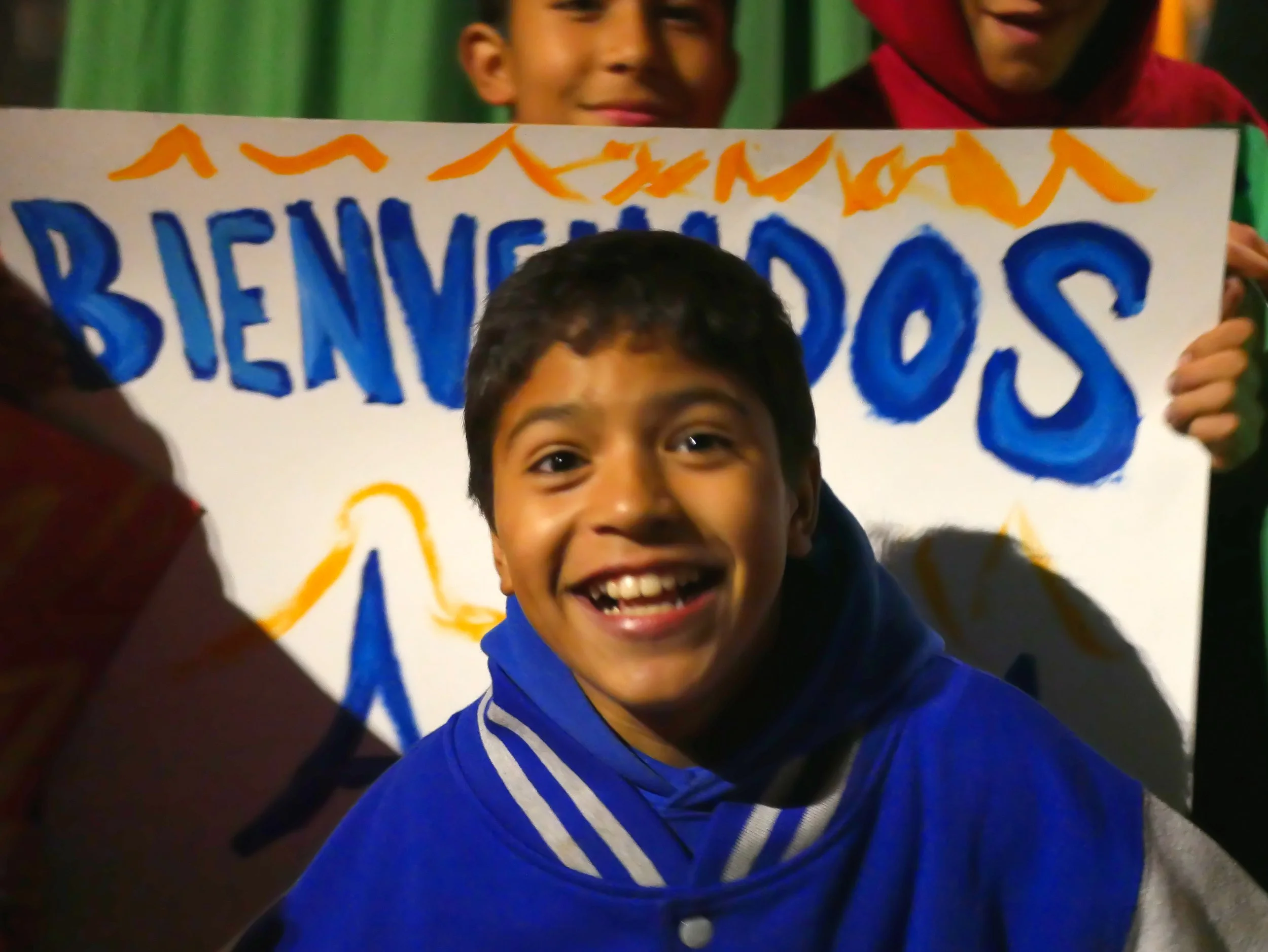 student stands in front of a sign smiling