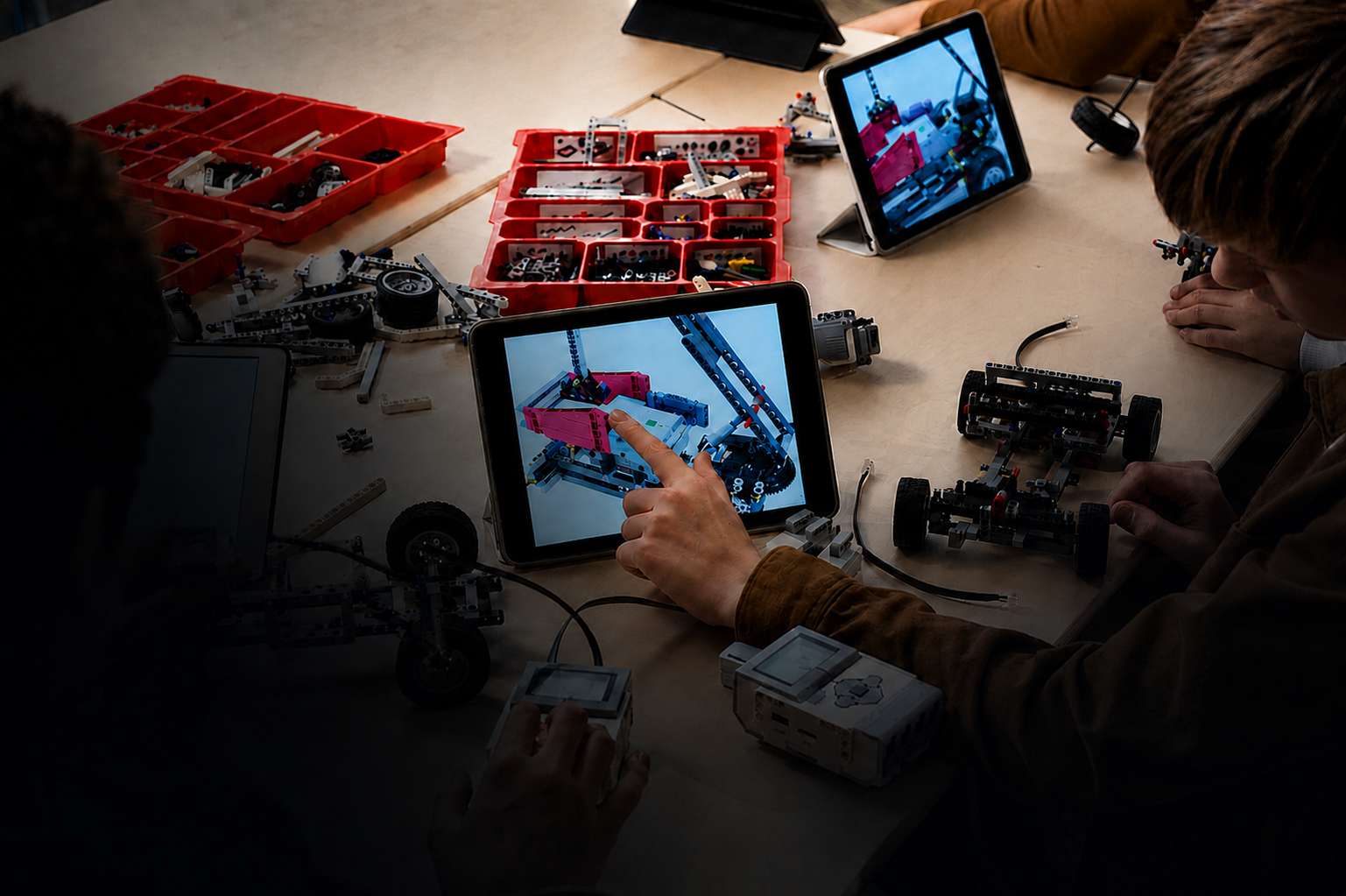 People working on robot construction with tablets and plastic building parts on a table.