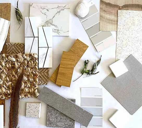Sample of various interior design materials including tile, wood, fabric, and paint swatches arranged on a white surface.