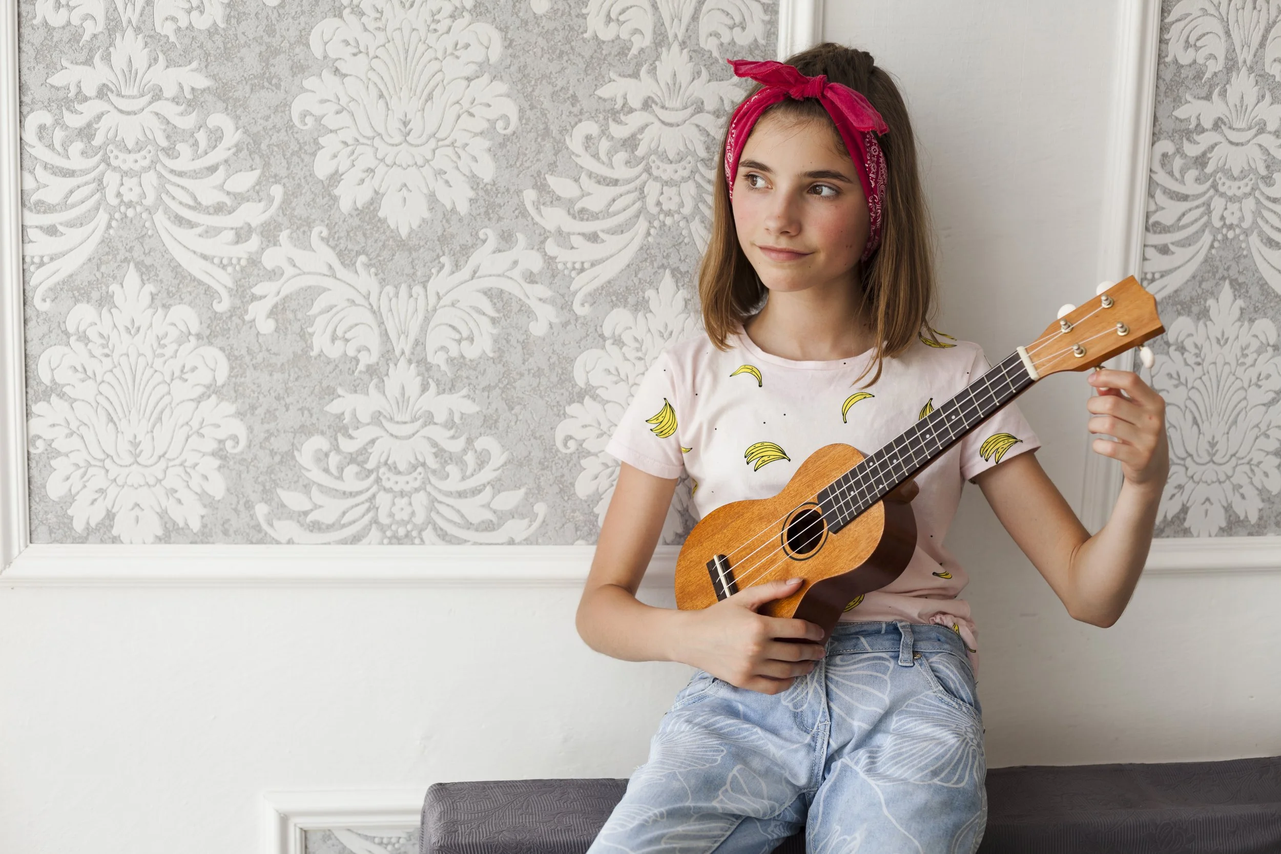smiling-girl-sitting-sofa-adjusting-ukulele-thinking.jpg