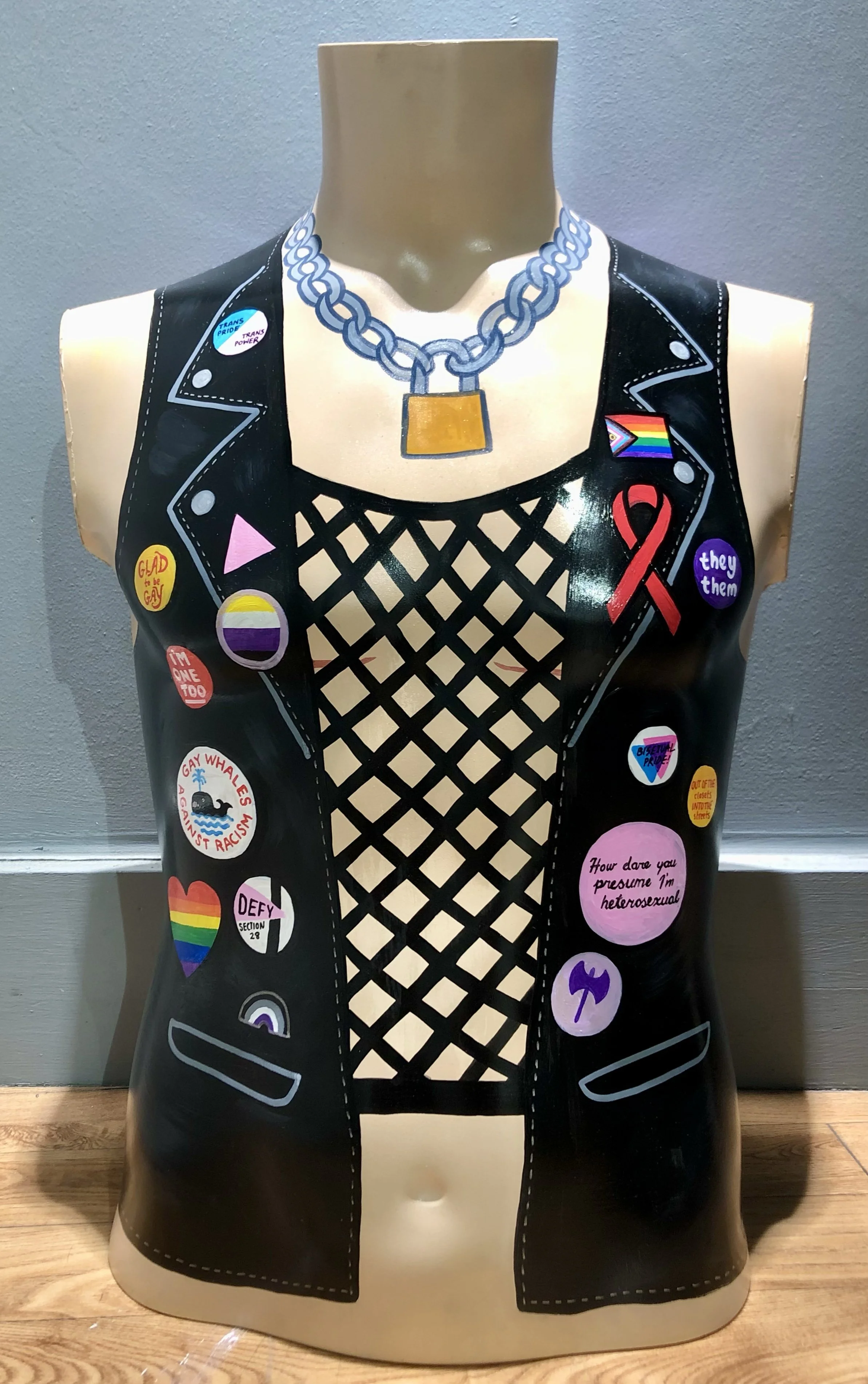 A male mannequin torso painted to look like a leather vest adorned with various queer and LGBTQ badges. Artwork by Hayley Wells for Chelmsford Art Trail