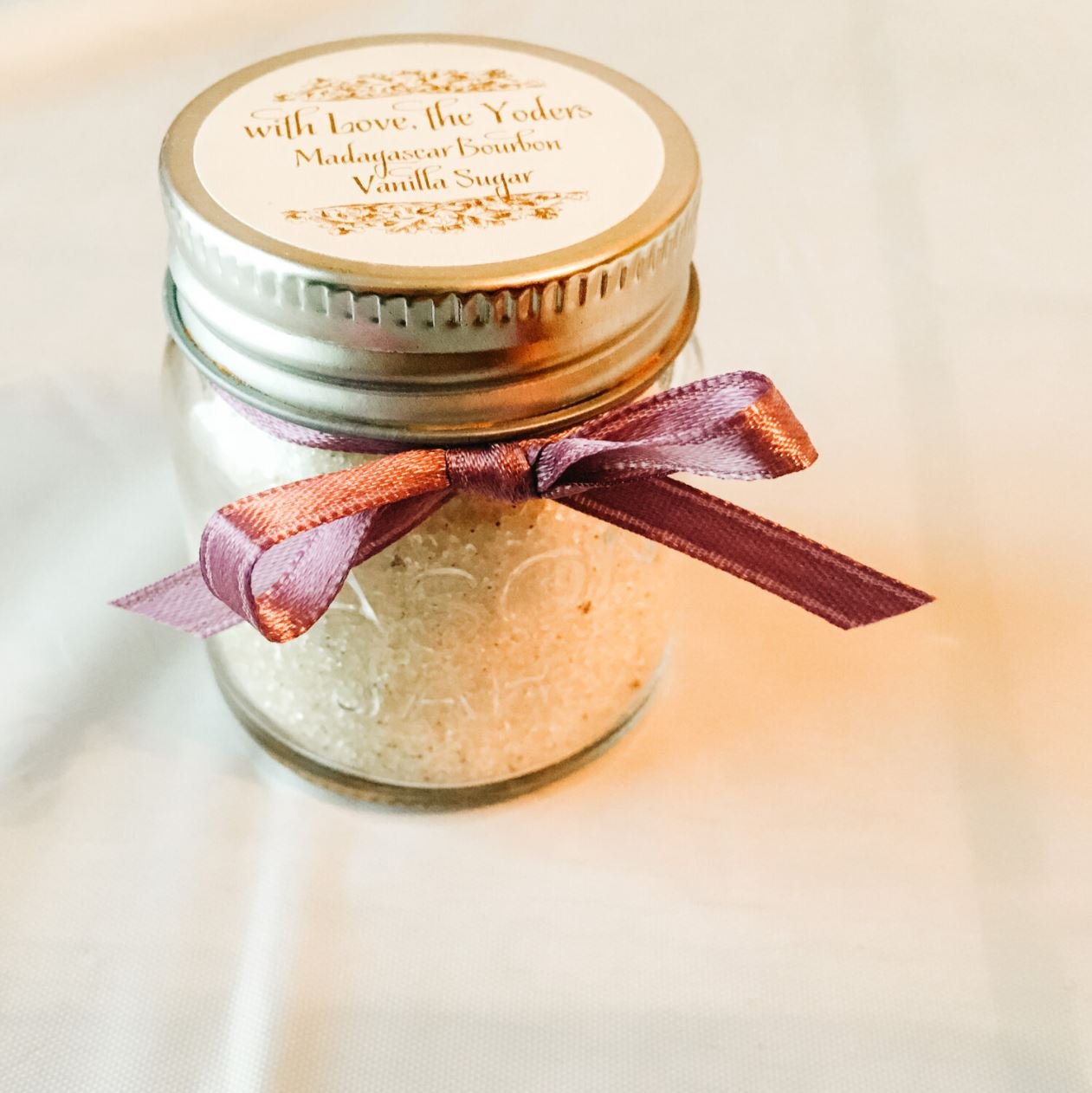 mason jar containing flavored sugar with a marron ribbon and a label that reads "with Love, the Yoders. Madagascar Burbon Vanilla Sugar"
