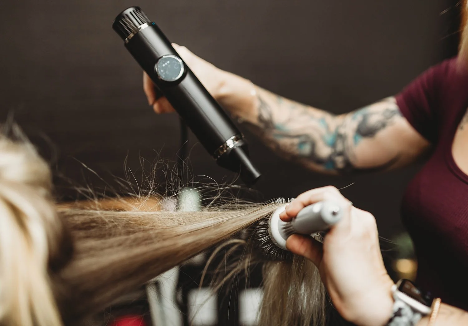 Upclose shot of a hairstylist blow drying client's hair for a business photoshoot