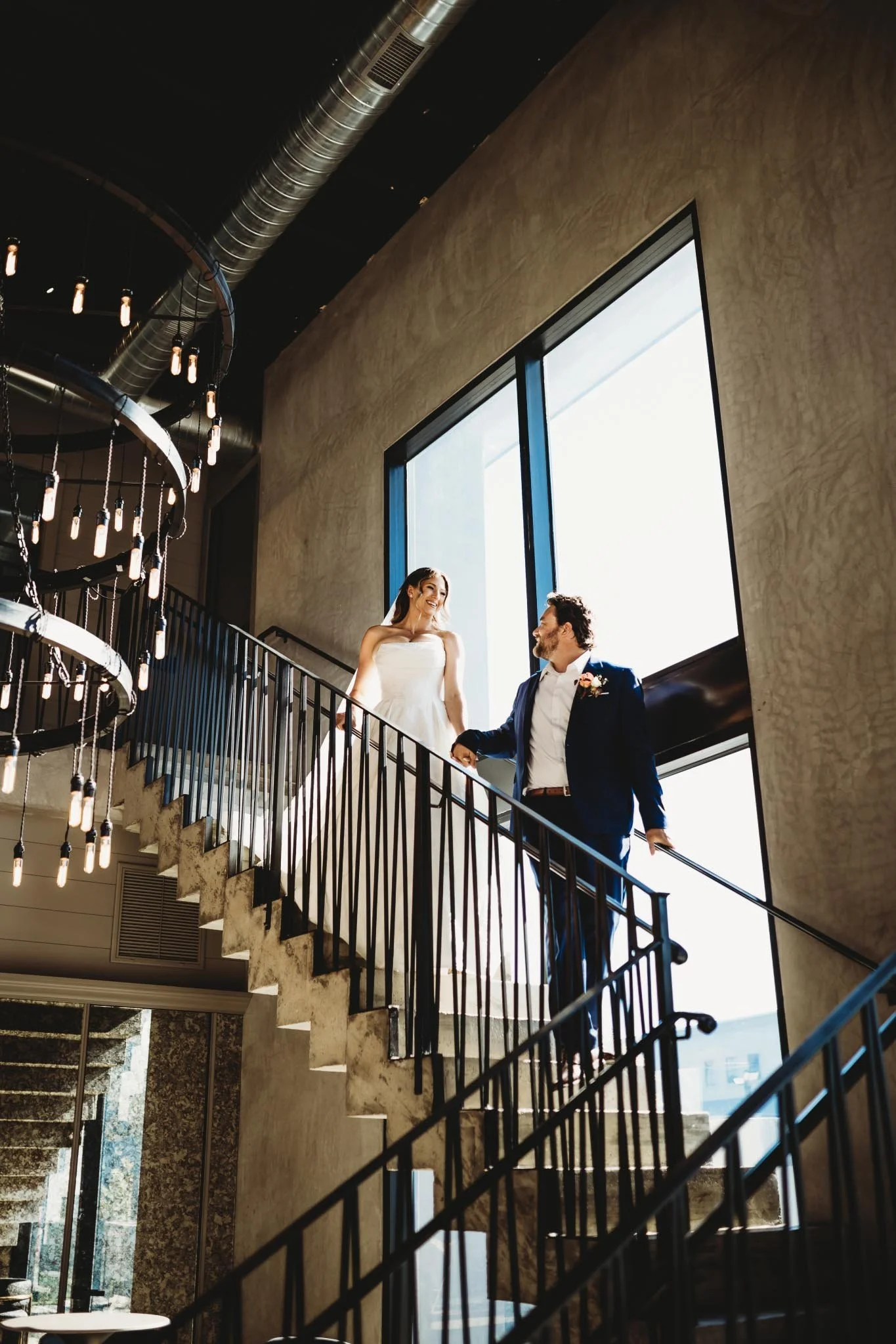 Bride and groom walking down the stairs at a modern wedding venue