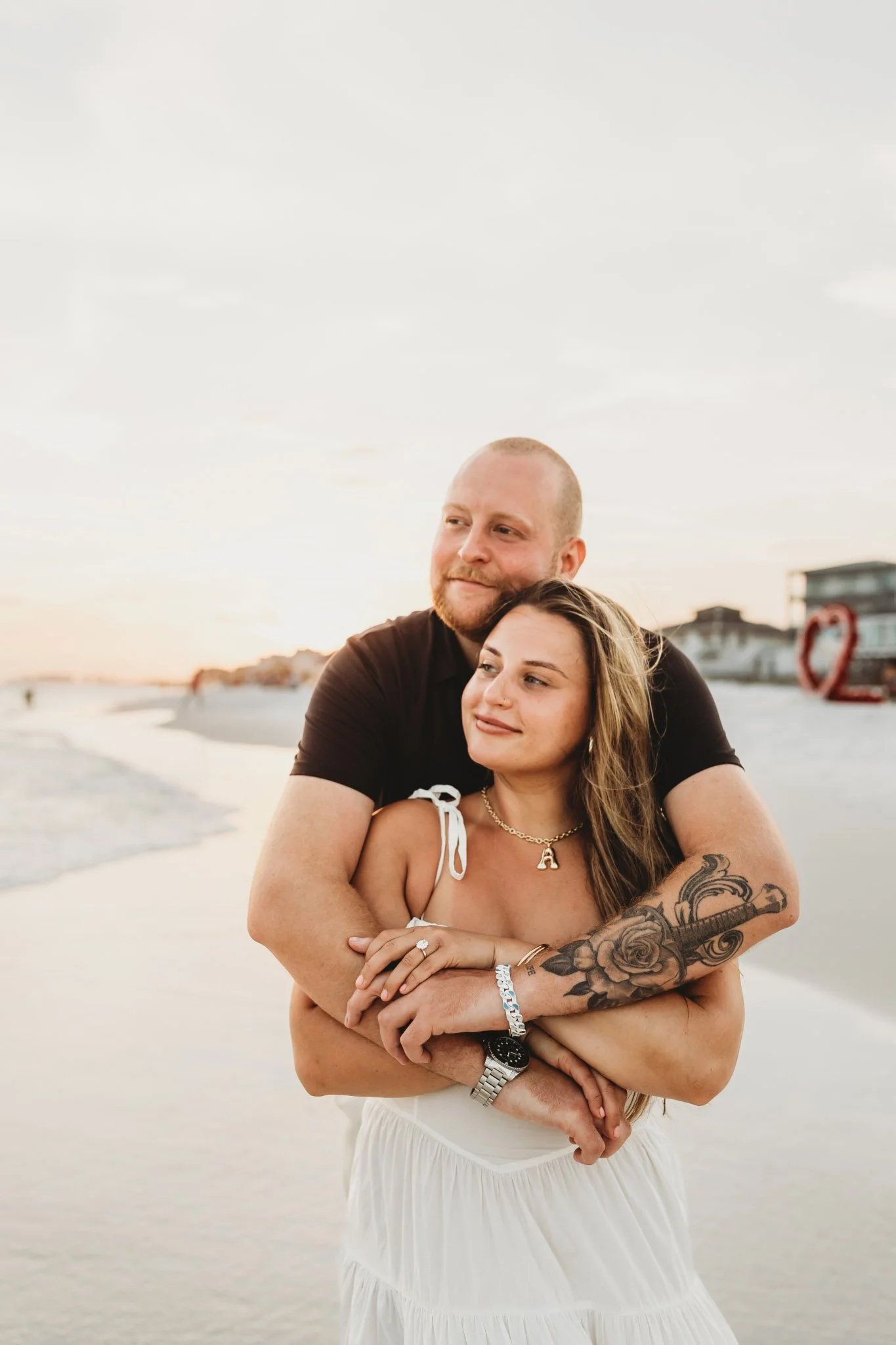 Engaged couple holding each other on the beach at sunset