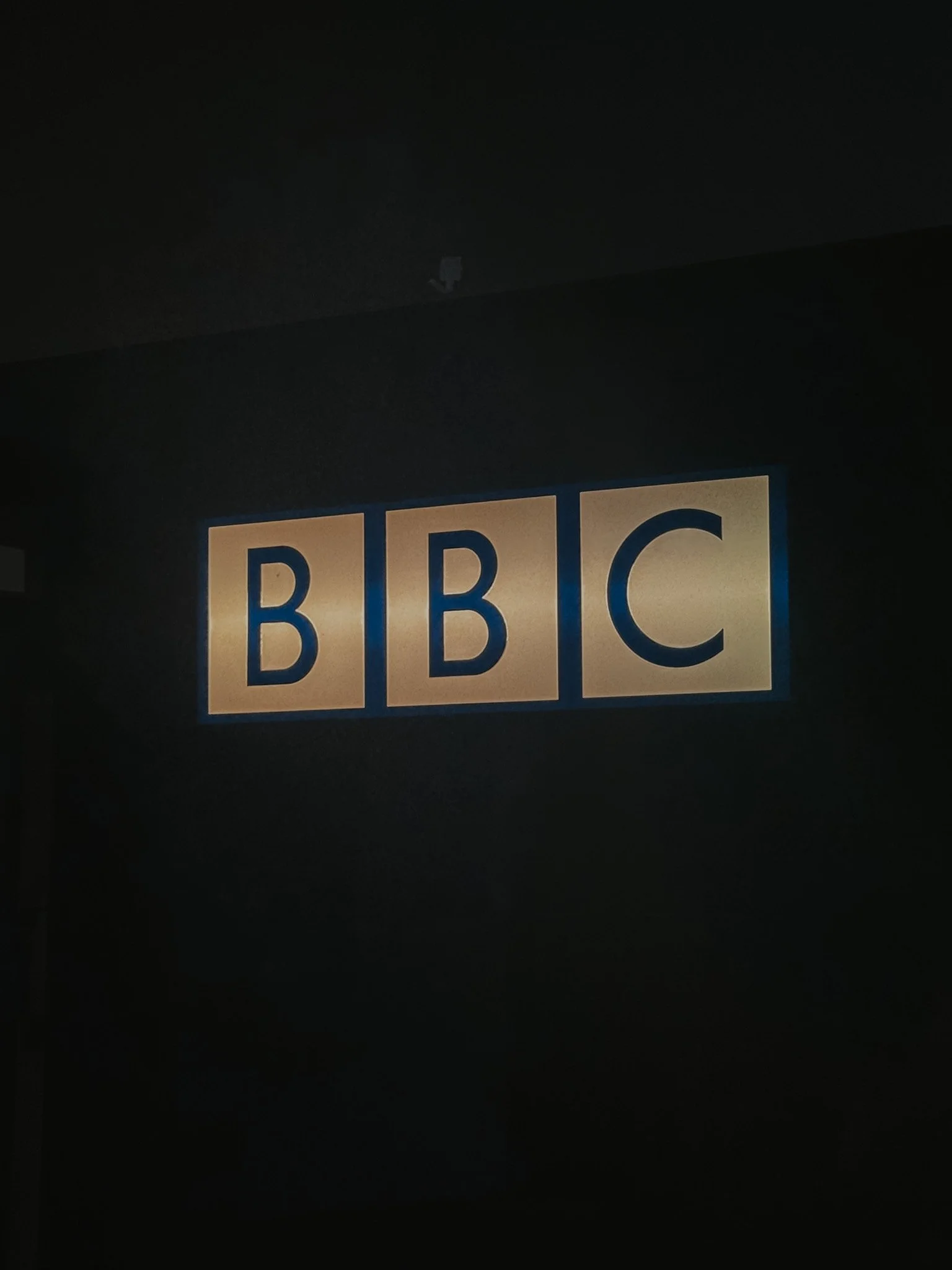 BBC logo displayed on a wall indoors, illuminated with backlighting.