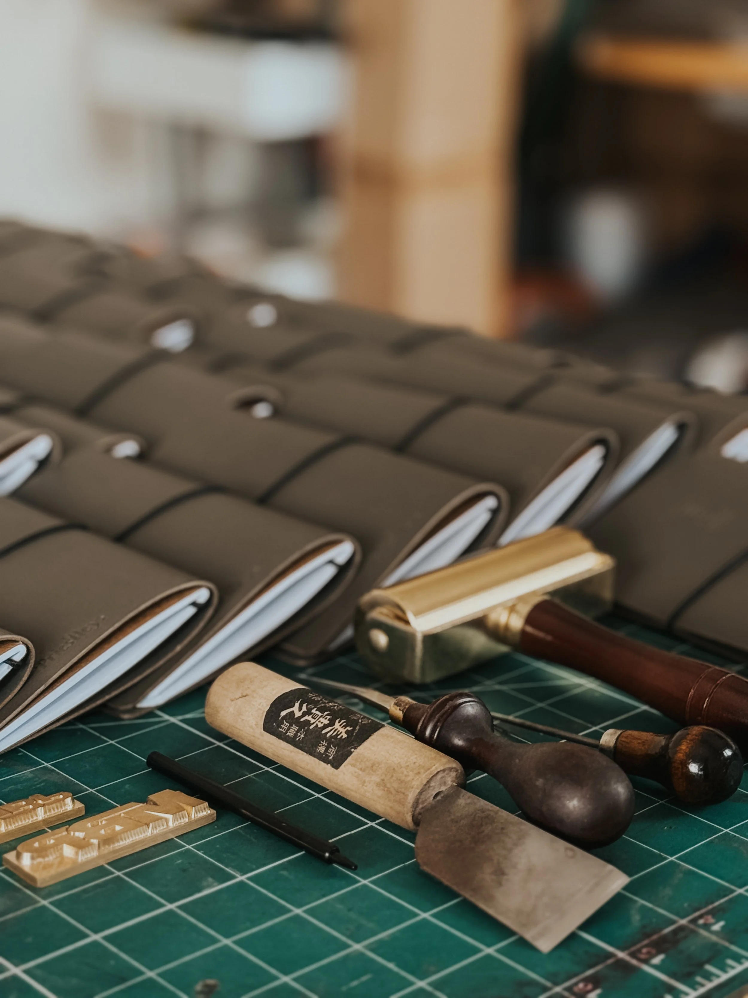 A green cutting mat with various woodworking tools, including chisels, a block plane, and wooden pieces with carvings.