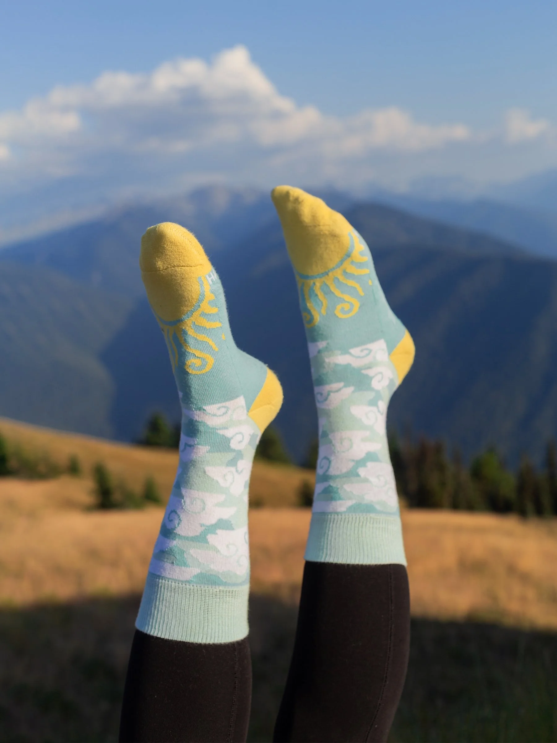 Happy Earth Perfect Day Socks featuring clouds and sun graphic on the toe in the color mint, white, and yellow