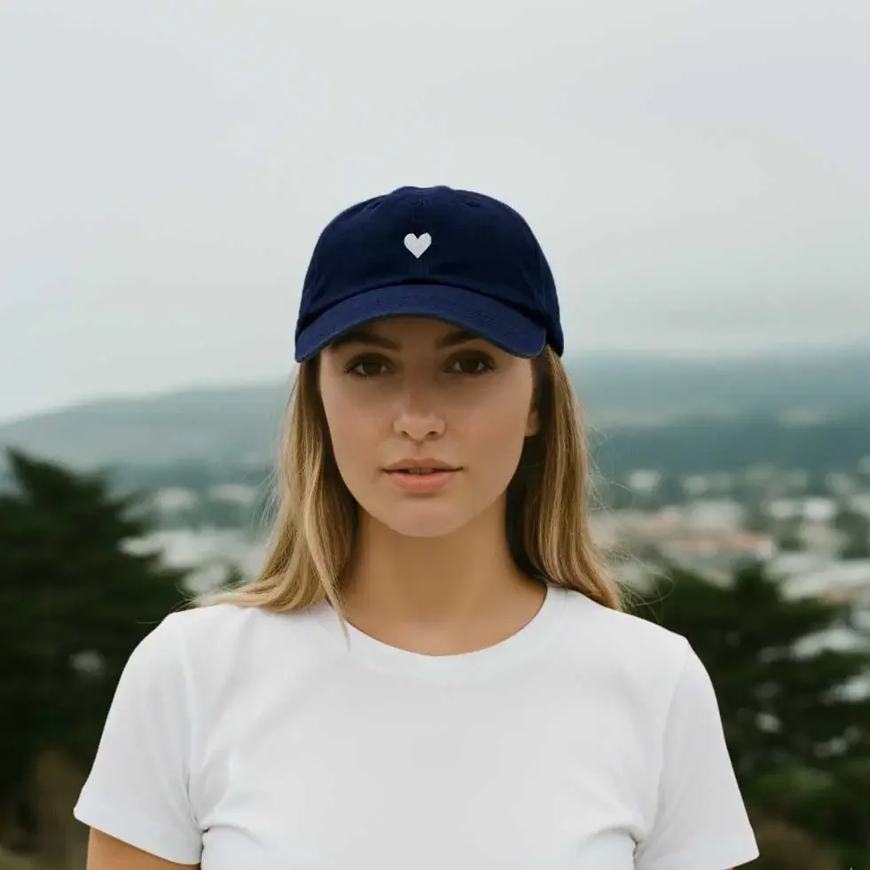 Atticus Poetry 100% cotton navy blue hat with an embroidered white heart in the center and "Love her, but Leave her wild on" the side.webp