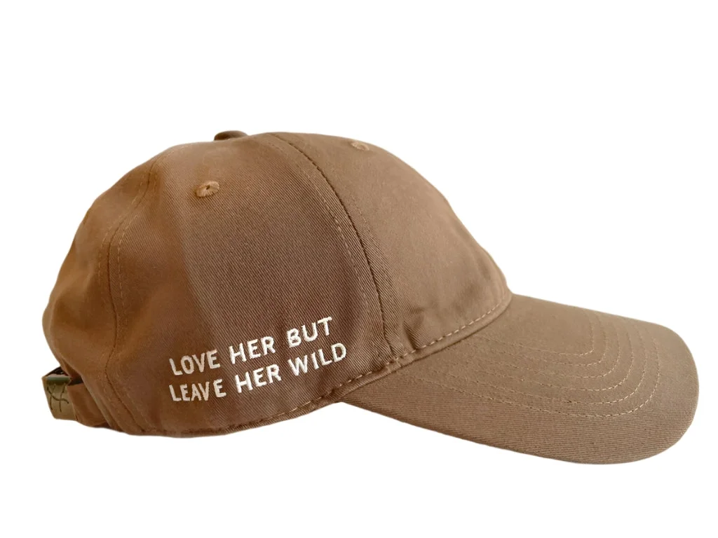 Atticus Poetry 100% cotton  pigment dyed dad hat in the color mocha with a white embroidered heart and the words "Love her, but leave her wild".webp