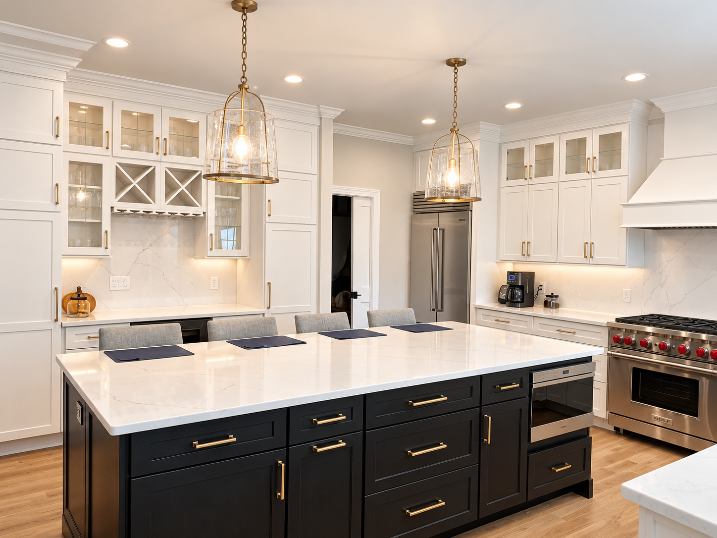 New construction kitchen design in Cranford, NJ by Elements Interior Design Studio. The cabinets are all white and then island cabinets are black. There are 2 brass and glass pendants over the island and 4 gray stools to the side of the island. 