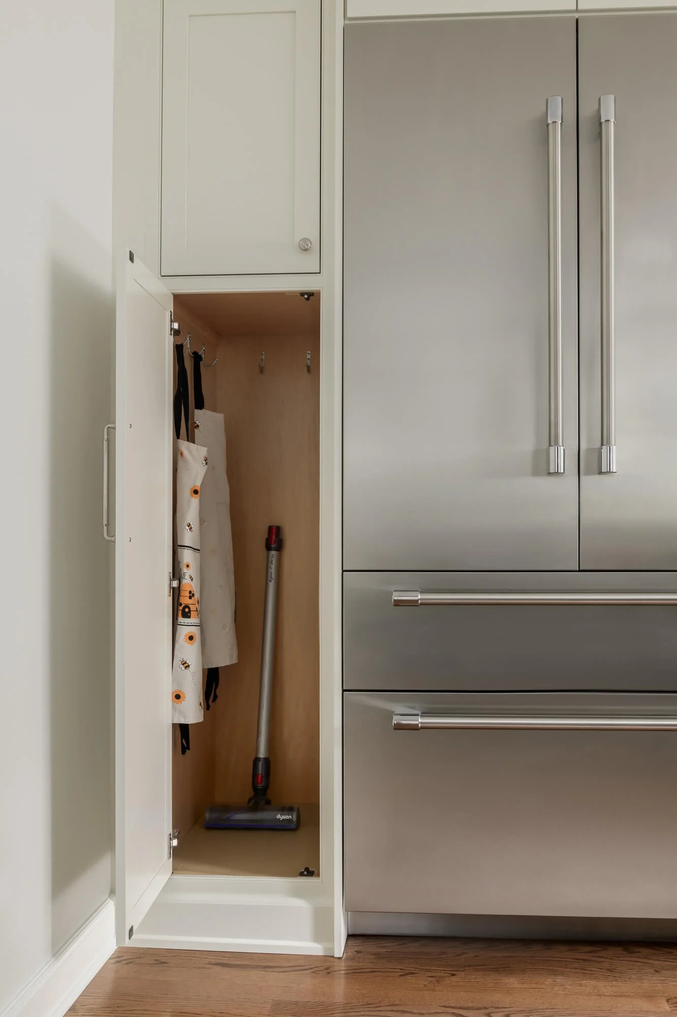 Utility cabinet next to the refrigerator as part of a kitchen renovation in Westfield, NJ by Elements Interior Design Studio.