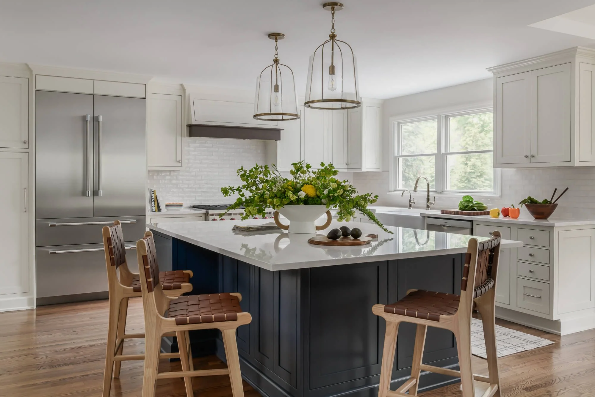 Wide view of white kitchen renovation featuring a large island with woven leather counter stools in Westfield, NJ by Elements Interior Design Studio.