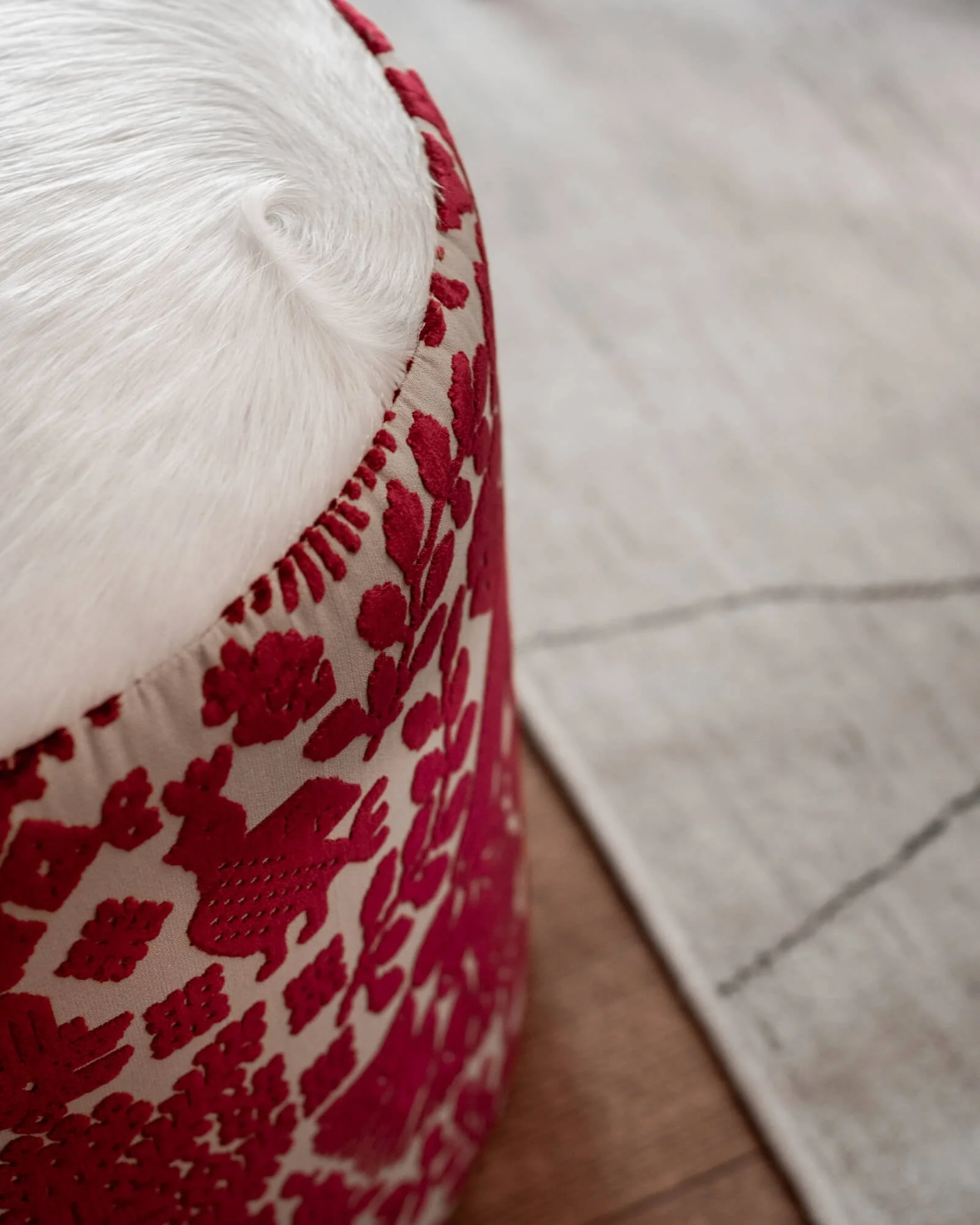 Close-up of a custom ottoman with a bright magenta patterned fabric on the sides and white horsehair on top.