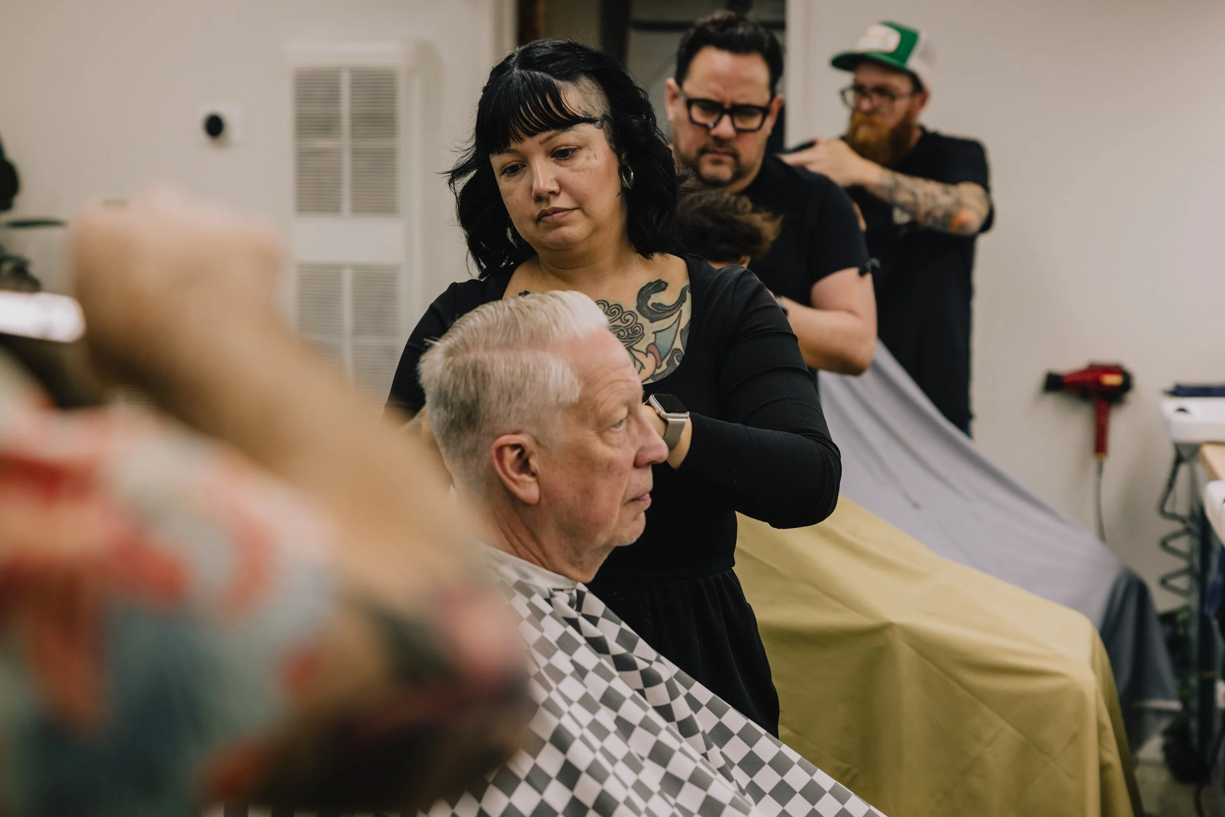 Barber styling an older client’s hair at Little Barber, a welcoming Austin barbershop for all ages.