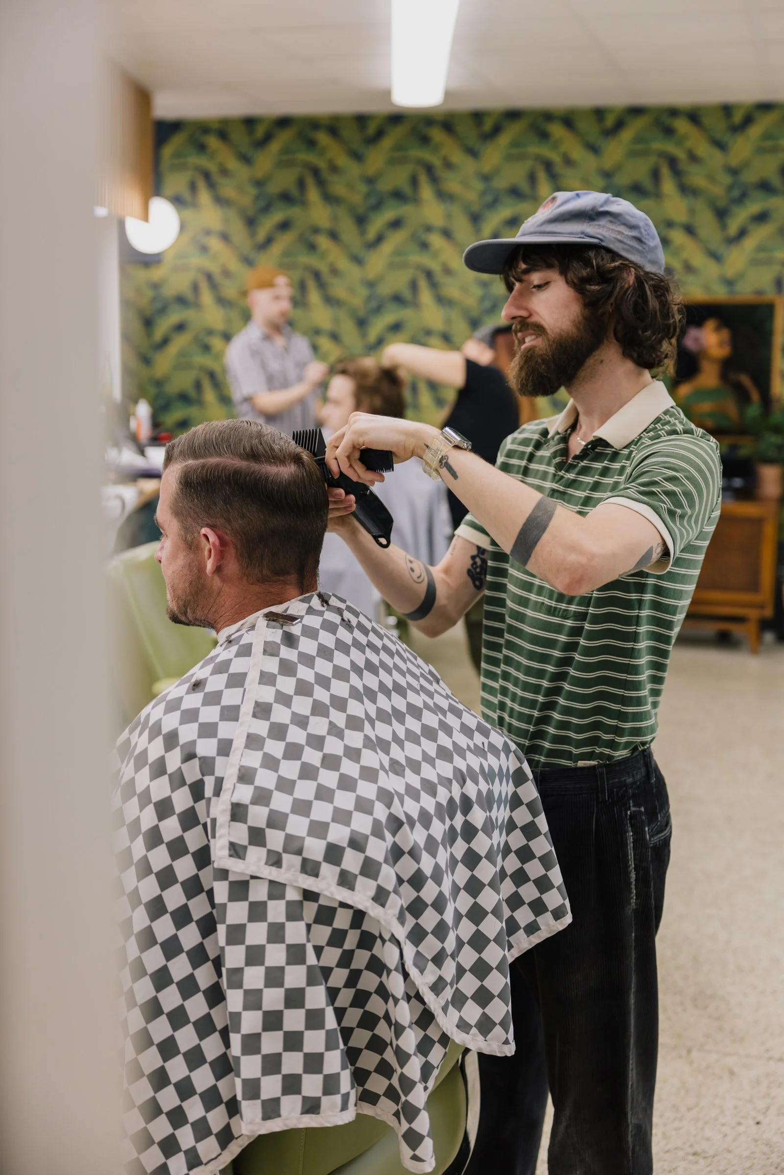 Barber cutting a client’s hair while another service happens in the background at Little Barber Austin.