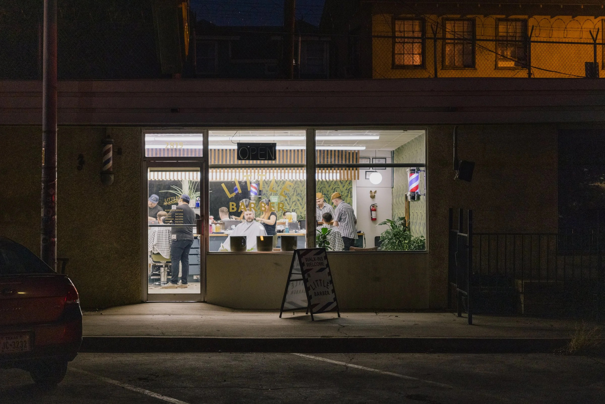 Front view of Little Barber Austin storefront at night, a neighborhood men’s barbershop.