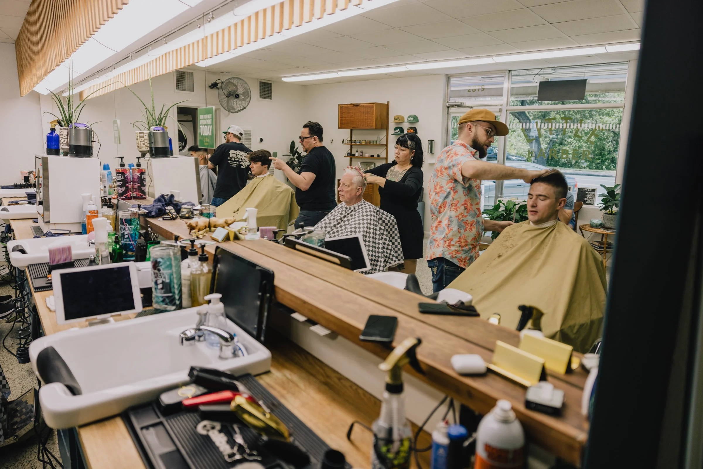 Busy day inside Little Barber in Austin Texas with multiple barbers delivering men’s haircuts.