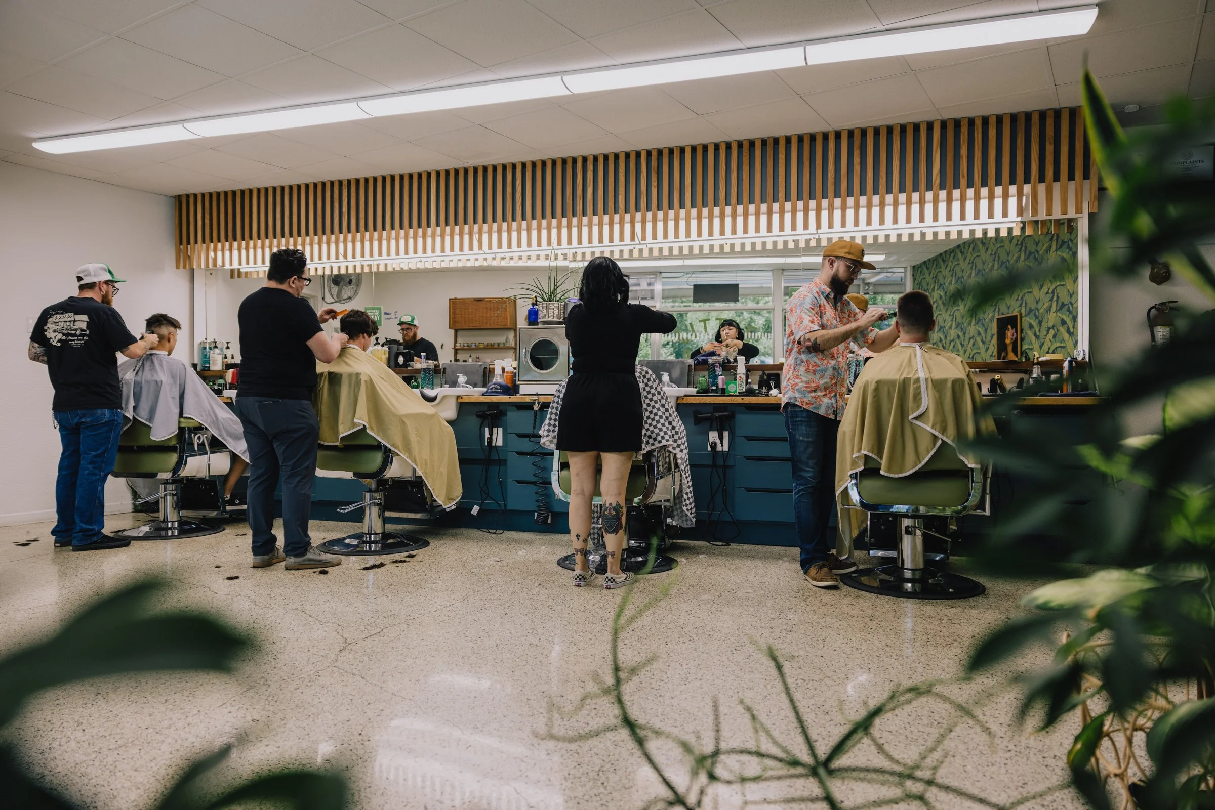 Wide interior view of Little Barber in Austin Texas with multiple barbers providing professional men’s grooming services.