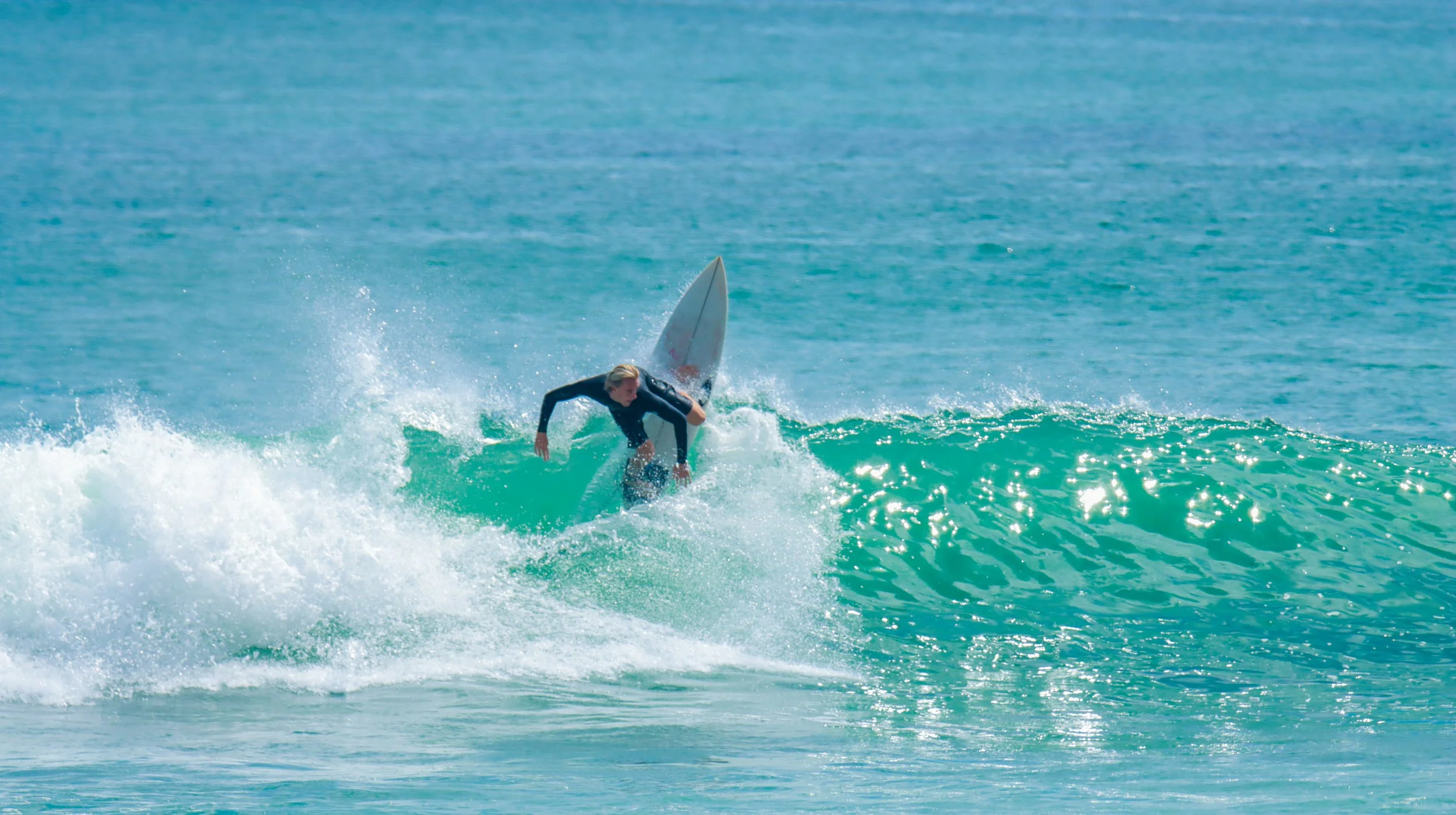 A person surfing on a wave in the ocean on a sunny day.