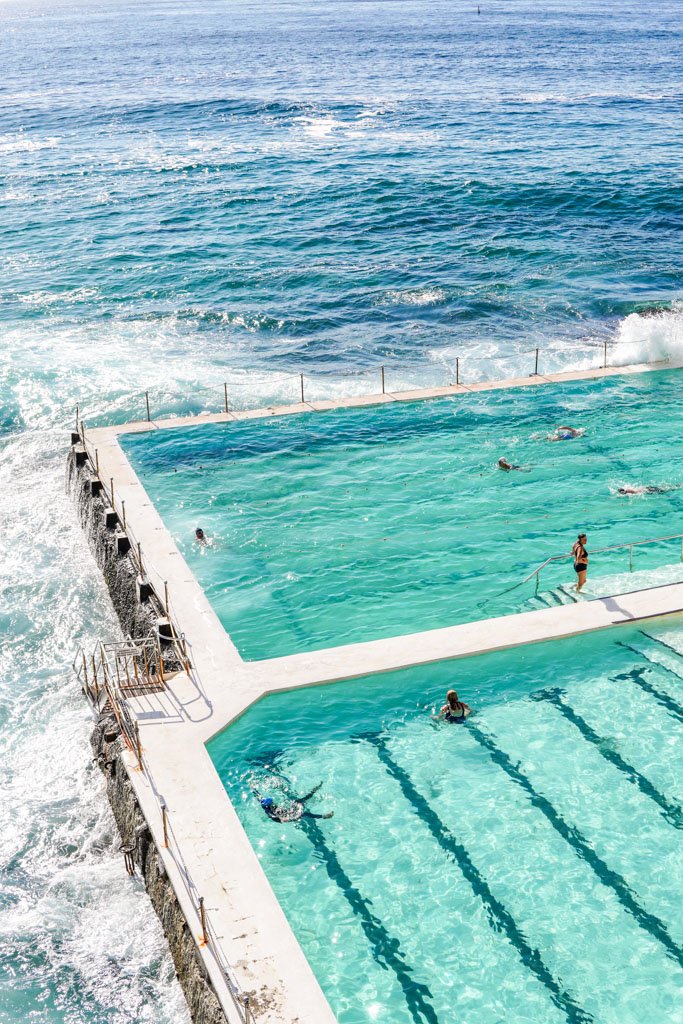 People swimming in an ocean pool with a view of the open sea.