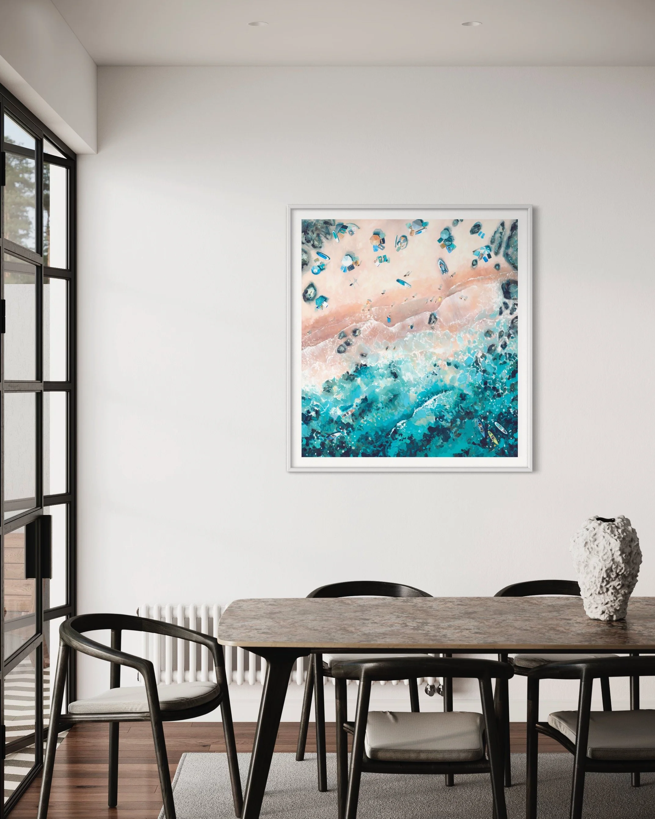 The Emerald Rock print in a large frame above a dining table, showcasing the vibrant turquoise green waves and coastal beauty of Salcombe