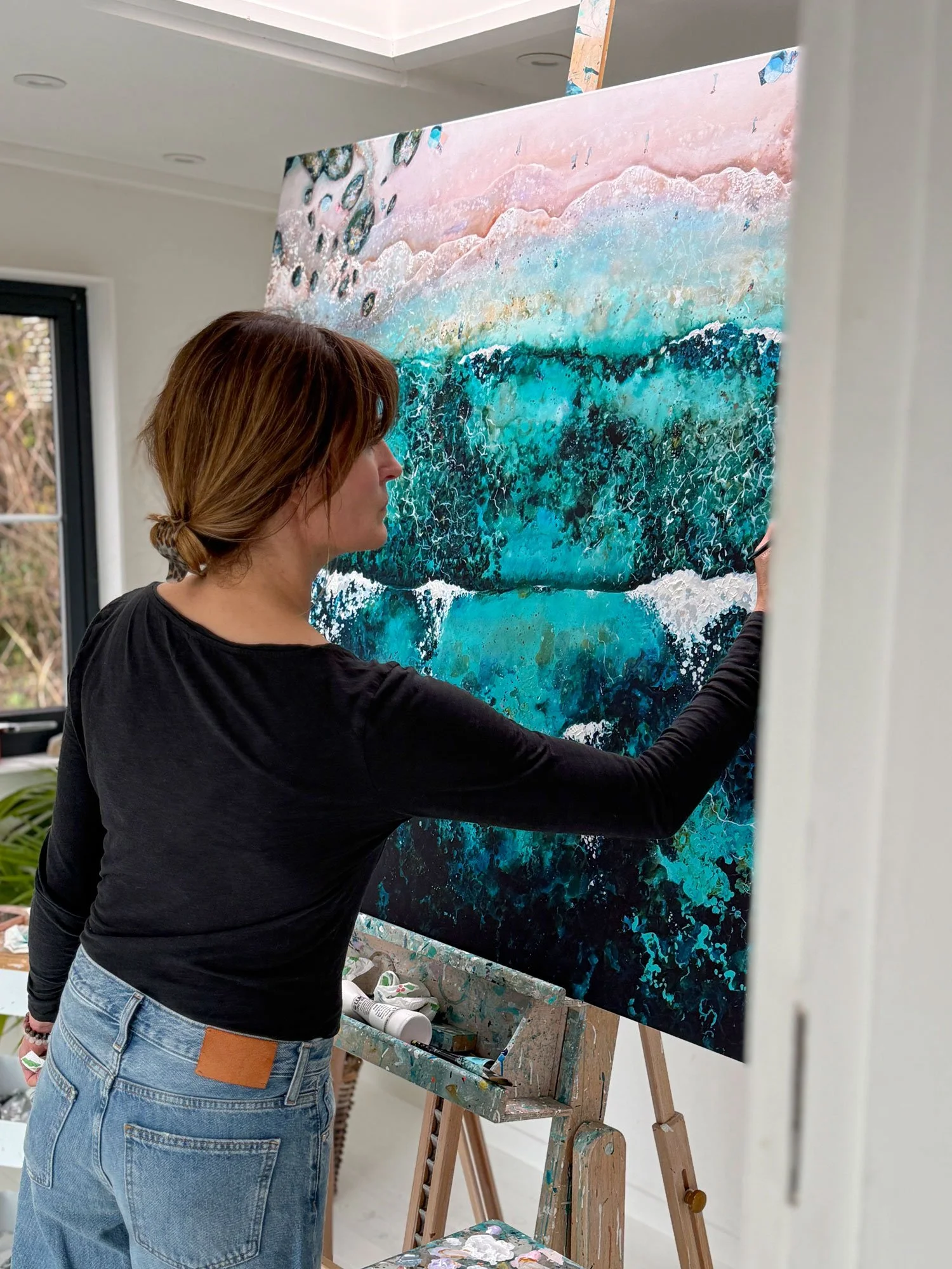 aerial seascape artist, Lucy Young, hand embellishing a canvas print