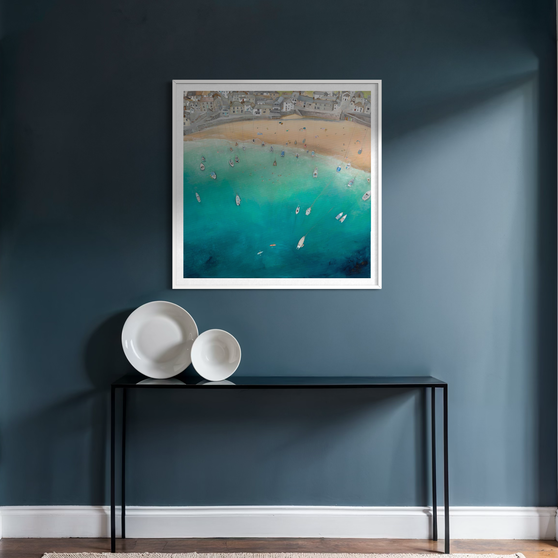 The Cornish Shores print styled in a dark blue coastal cottage hallway, capturing the historic charm of Mousehole, Cornwall