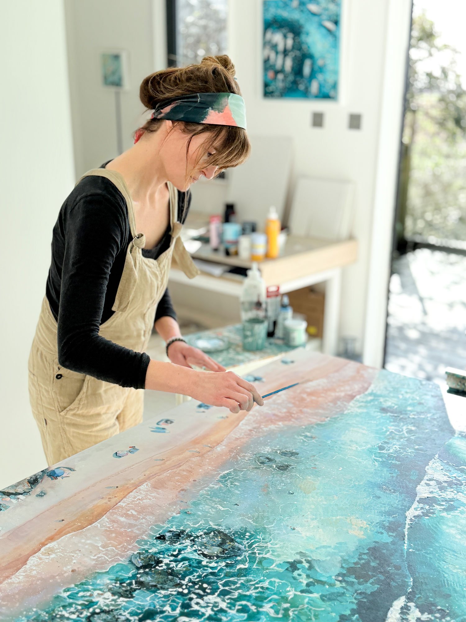 Professional British coastal artist Lucy Young painting an original aerial seascape with 24k gold leaf in her studio.