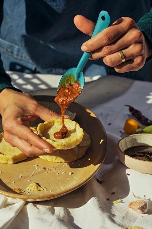 Person scooping meat sauce into a bread bowl.