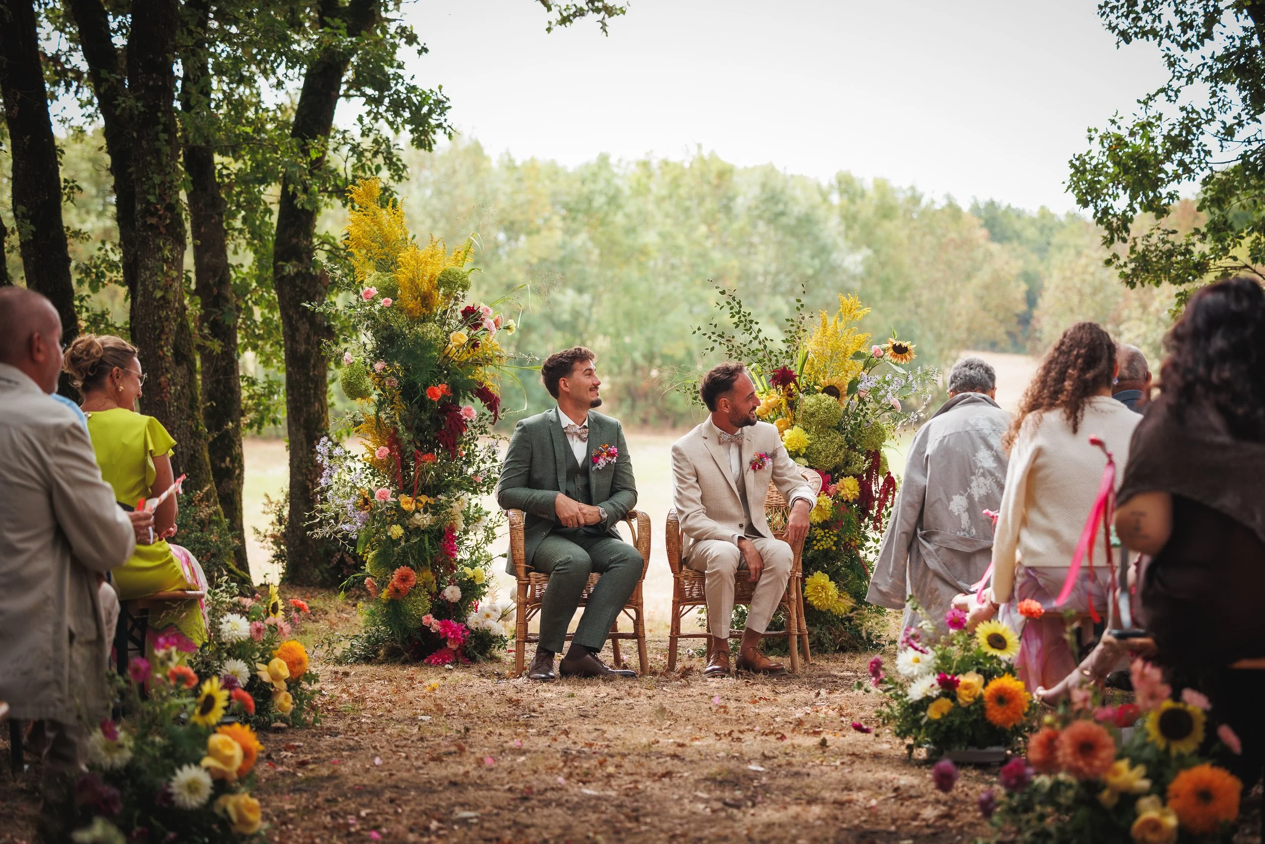 Couple de garçons mariés, en pleine nature, arche fleurie, colorée, cérémonie laïque