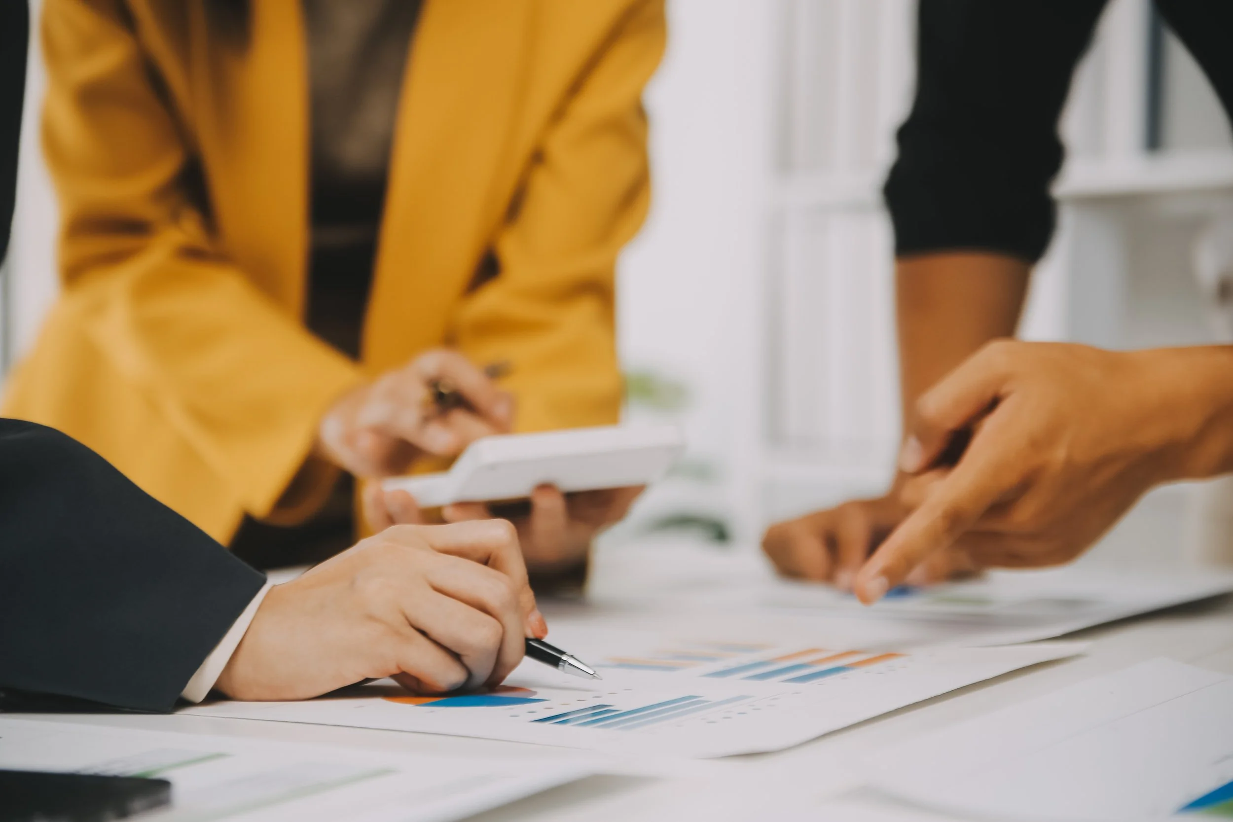 close up of hands pointing at financial stats in a business meeting