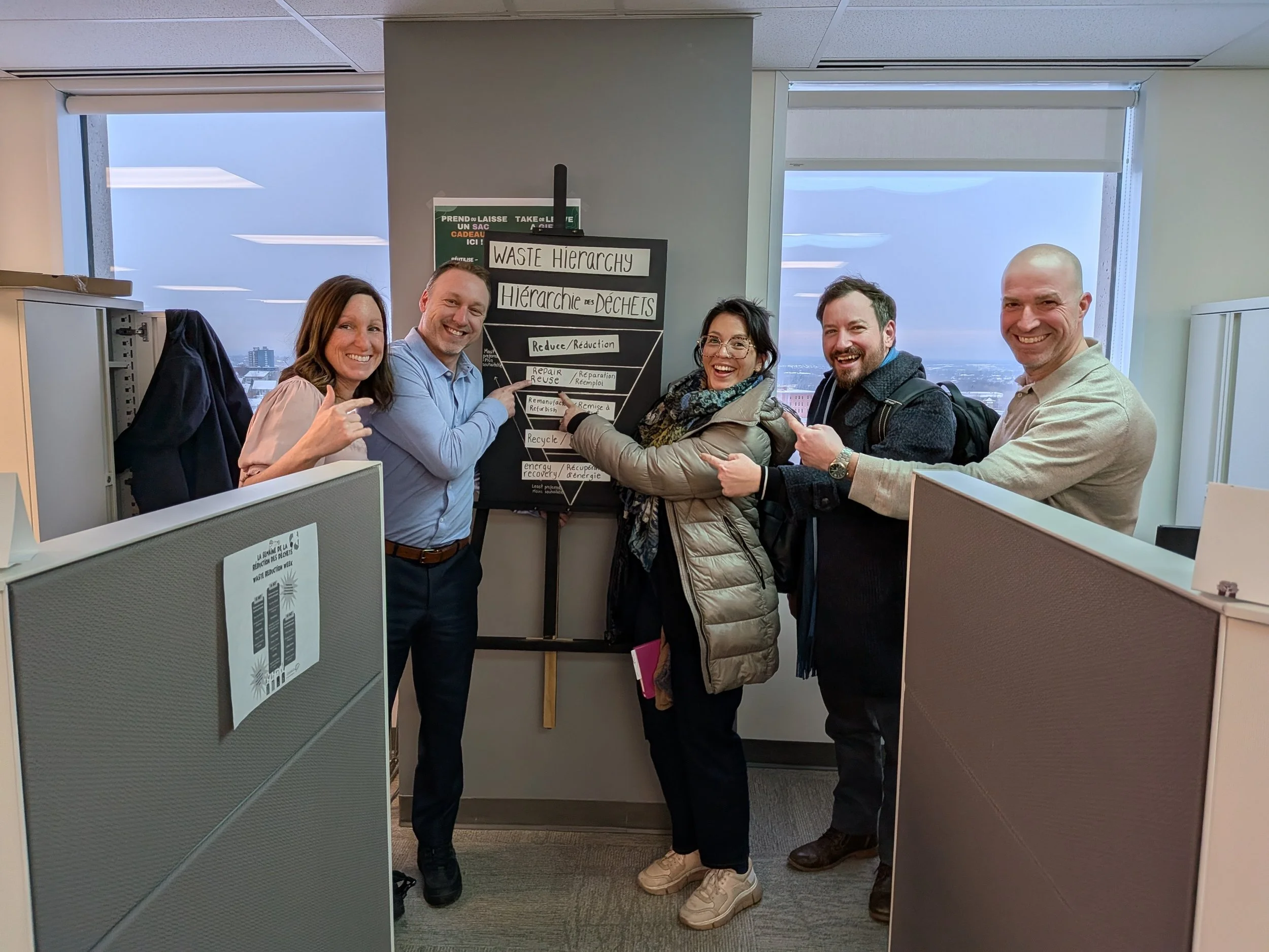 5 people pointing at a sign that says "reduce and reuse"