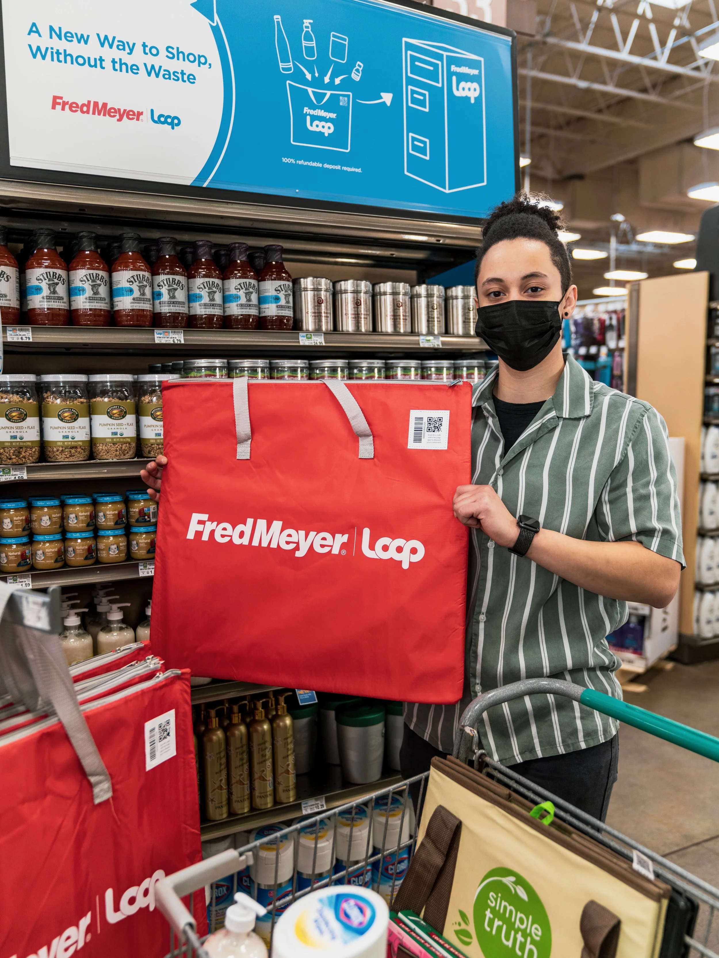 shopper with a red reusable tote bag in front of grocery shelves with reusable packaging