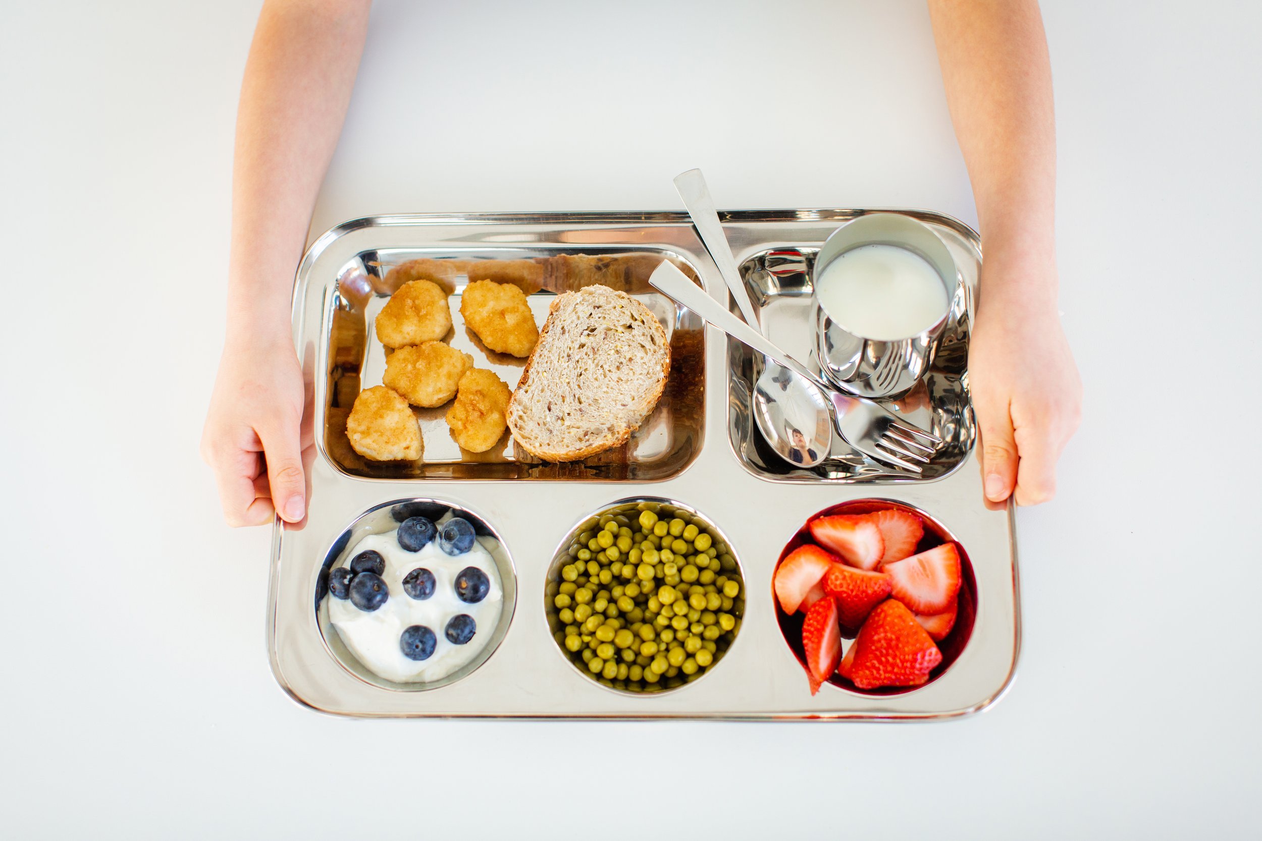 kid's hands holding stainless steel lunch tray
