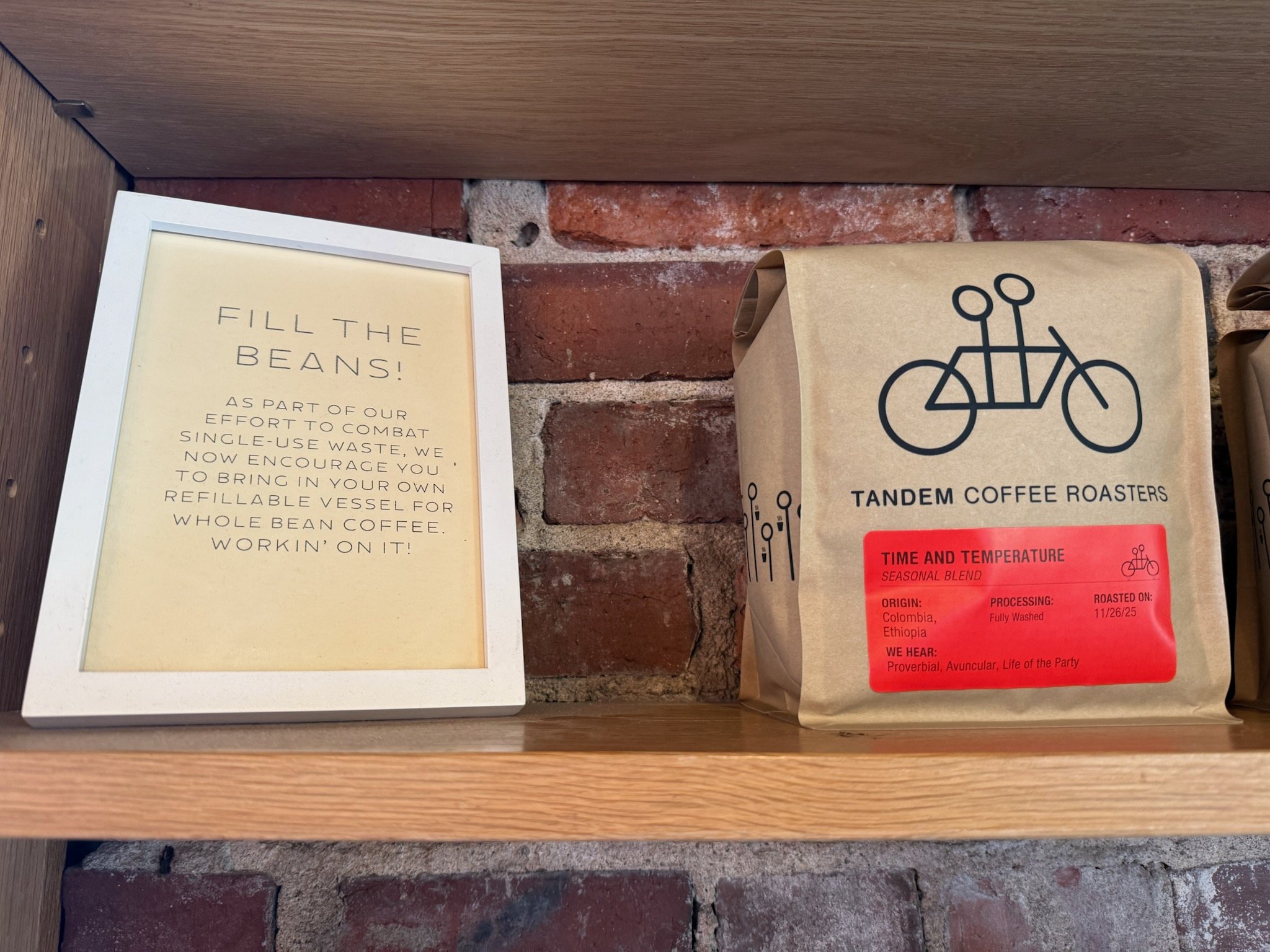 bag of coffee beans next to a sign encouraging reusable mugs
