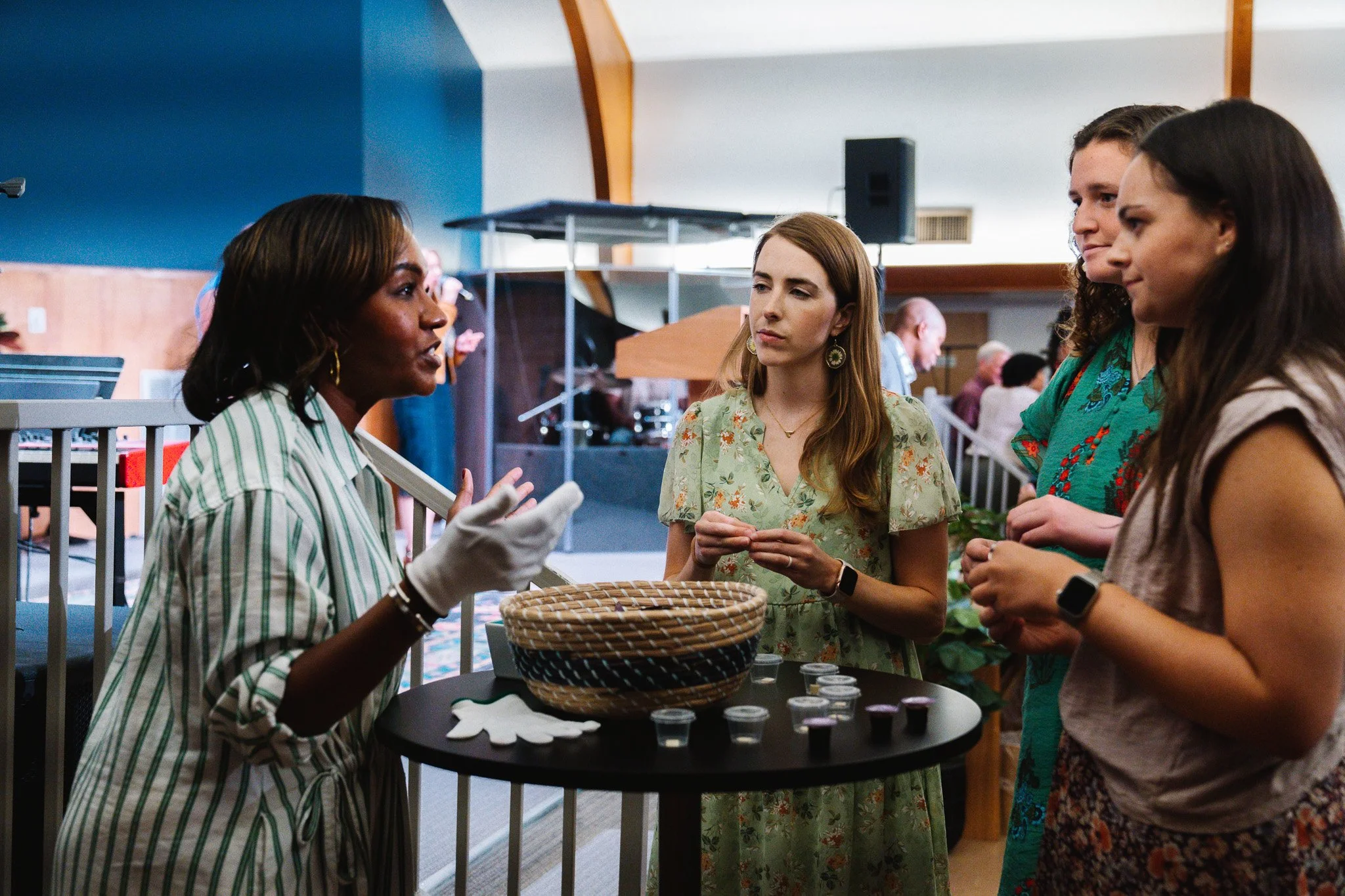 Woman administering Communion prayer and blessing to three young adult women