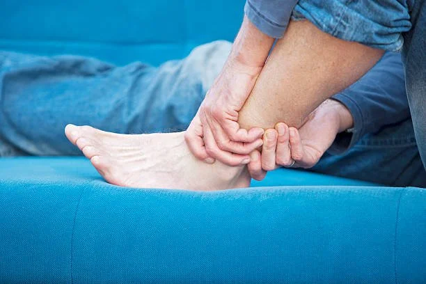 A person receiving a foot massage or physical therapy from another person on a blue couch.