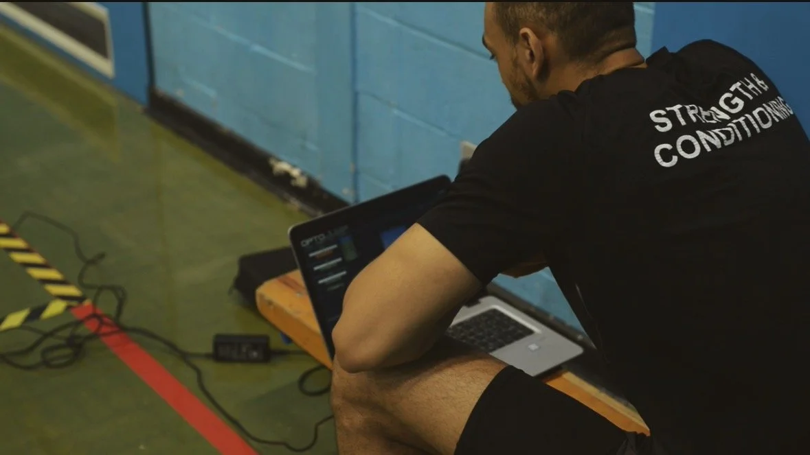 Strength and conditioning coach evaluating jump height and lower body power during athlete performance assessment