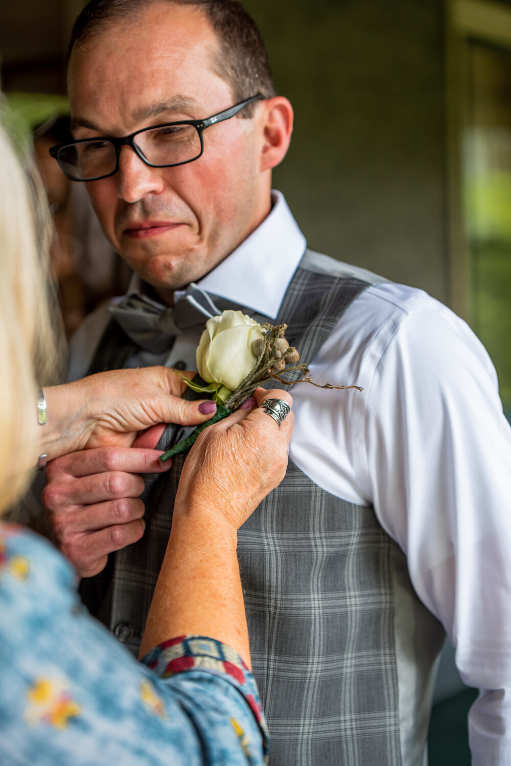 Groom having his boutonniere adjusted at Inn on Montford