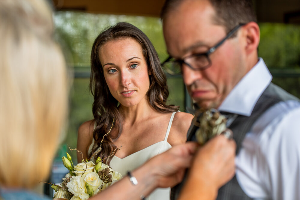 Bride watching boutonniere pinning during intimate wedding in Asheville, NC
