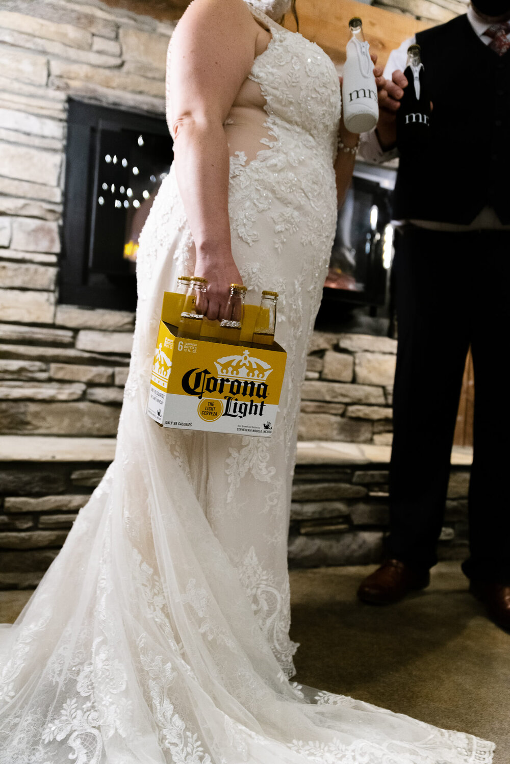 Bride holding case of corona light beer bottles in her wedding dress at The Parker Mill in Whittier, NC