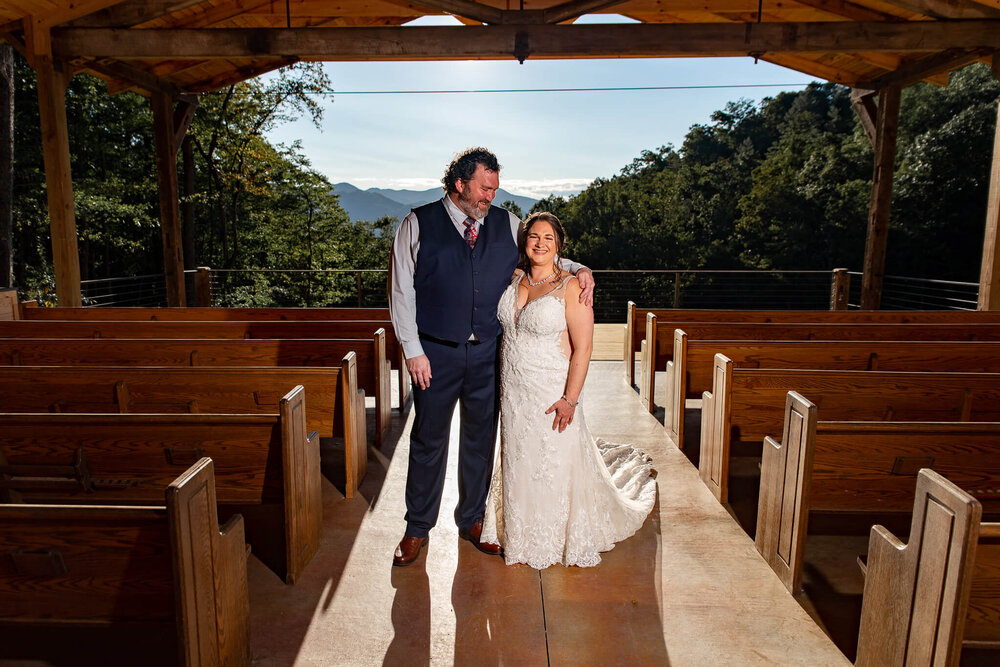 Mountain top wedding pavilion with bride and groom posing underneath it at The Parker Mill in Whittier, North Carolina