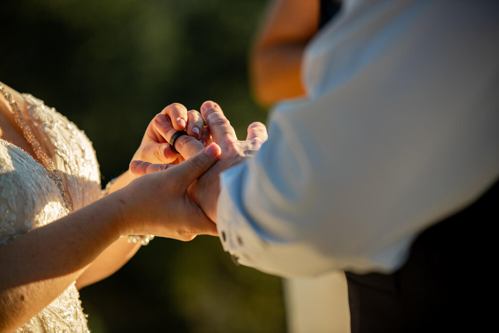 Bride placing wedding band on groom's finger at The Parker Mill